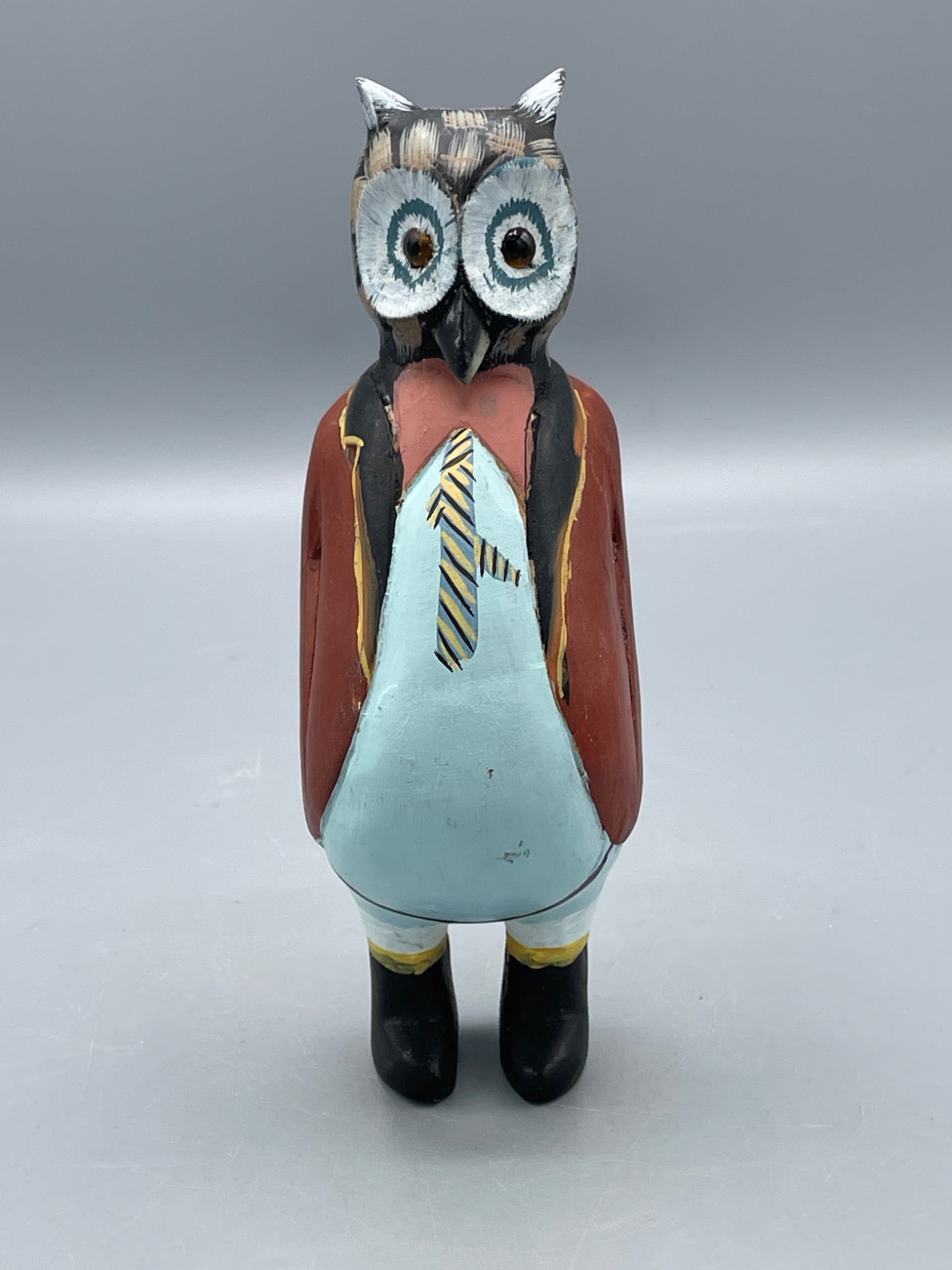Hand-Carved and Painted Wooden Owl Figurine in Anthropomorphic Style: This wooden owl figurine is hand-carved and painted, featuring an anthropomorphic design dressed in a suit with a tie. The piece measures approximately 7 inches in height and includes detailed