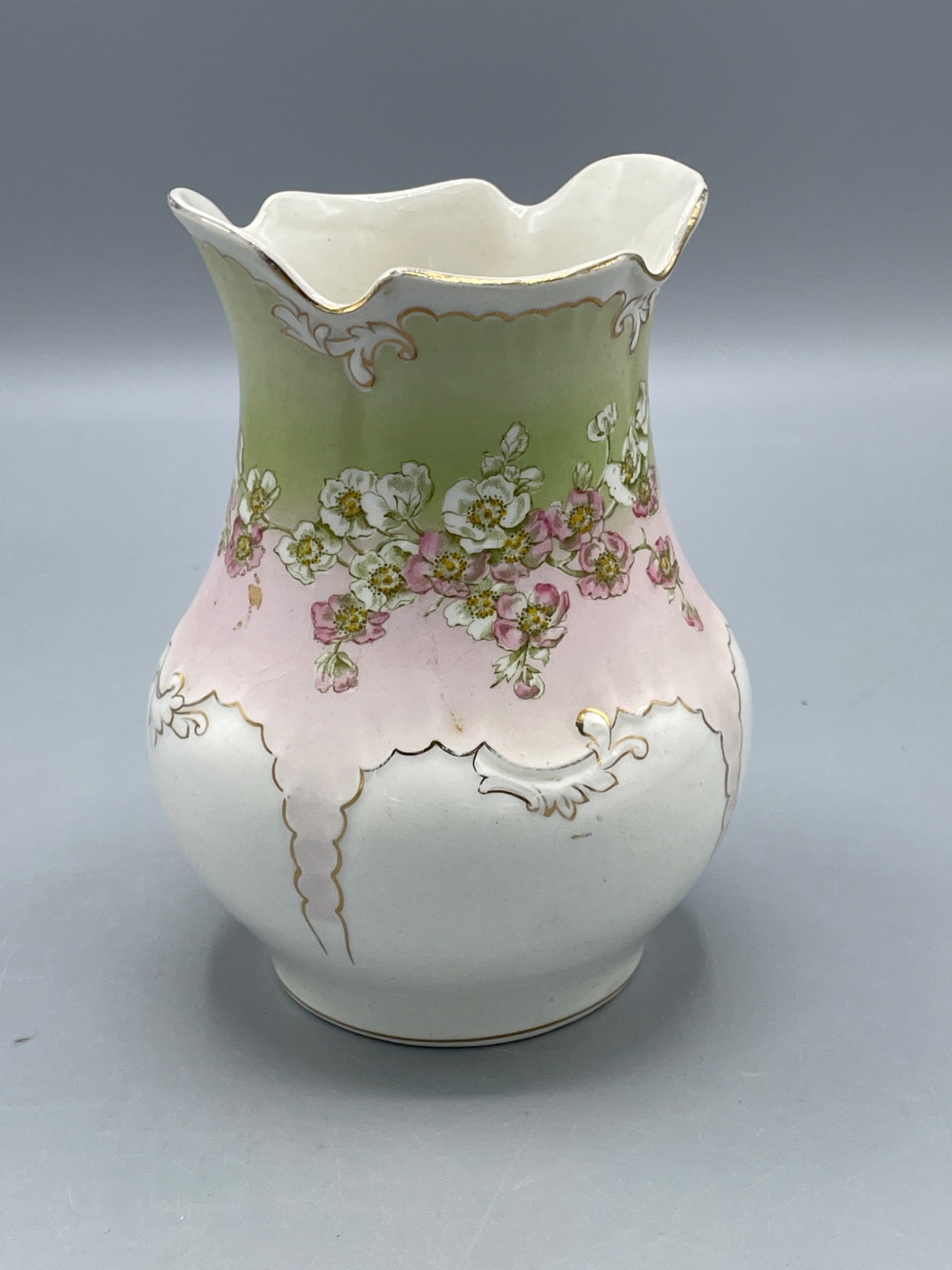 Porcelain Vase With Floral Design and Gold Detailing, Approx. 6 Inches Tall: A porcelain vase featuring a floral design with green and pink gradient tones, accentuated by gold detailing along the edges. The vase measures approximately 6 inches in height and has no visible