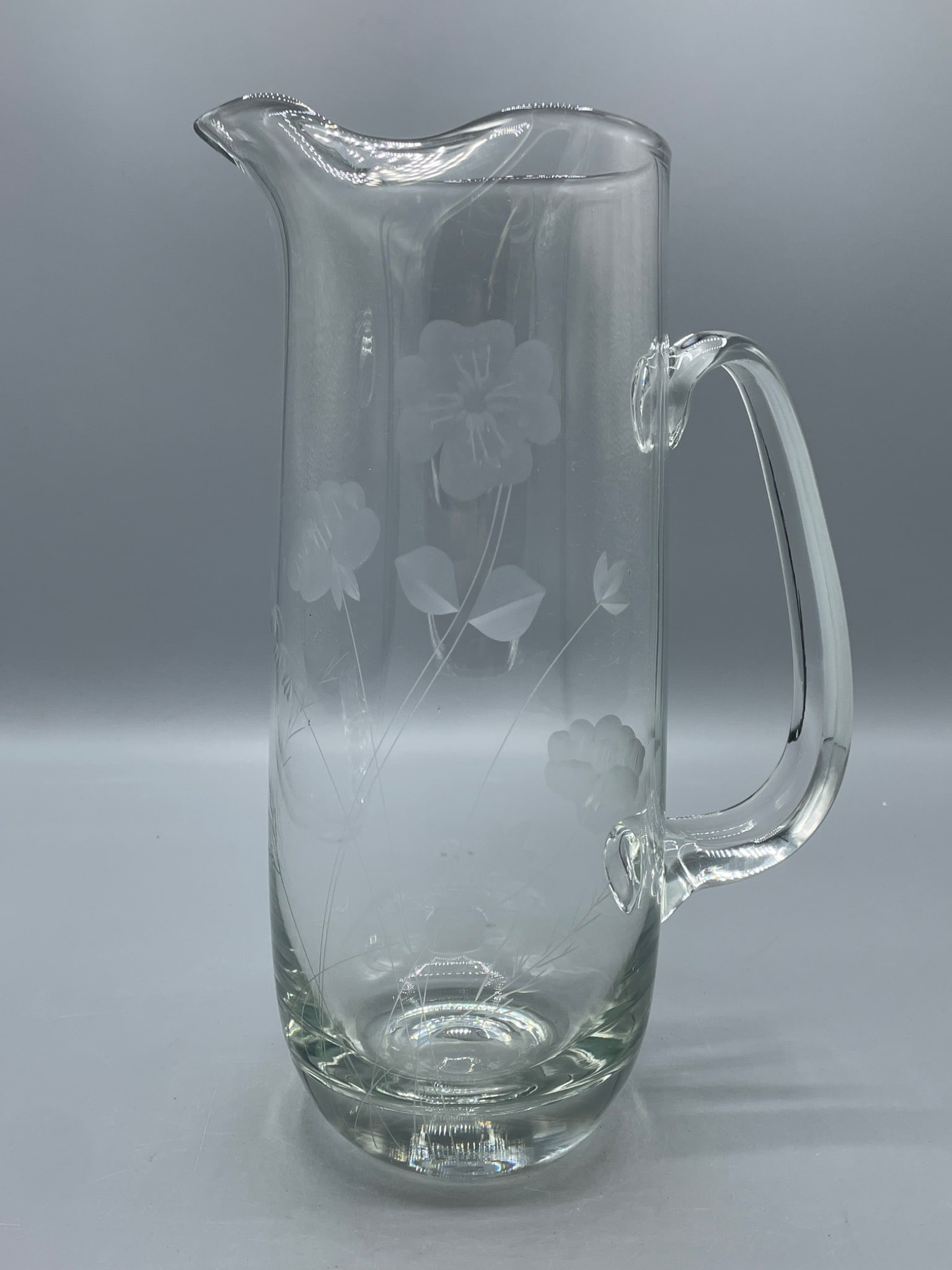 Clear Glass Pitcher with Etched Floral Design and Handle, 10-inch Height: This is a clear glass pitcher featuring an etched floral design on the sides. It includes a handle for ease of use and a spouted top for pouring. The pitcher measures approximately 10 inches in
