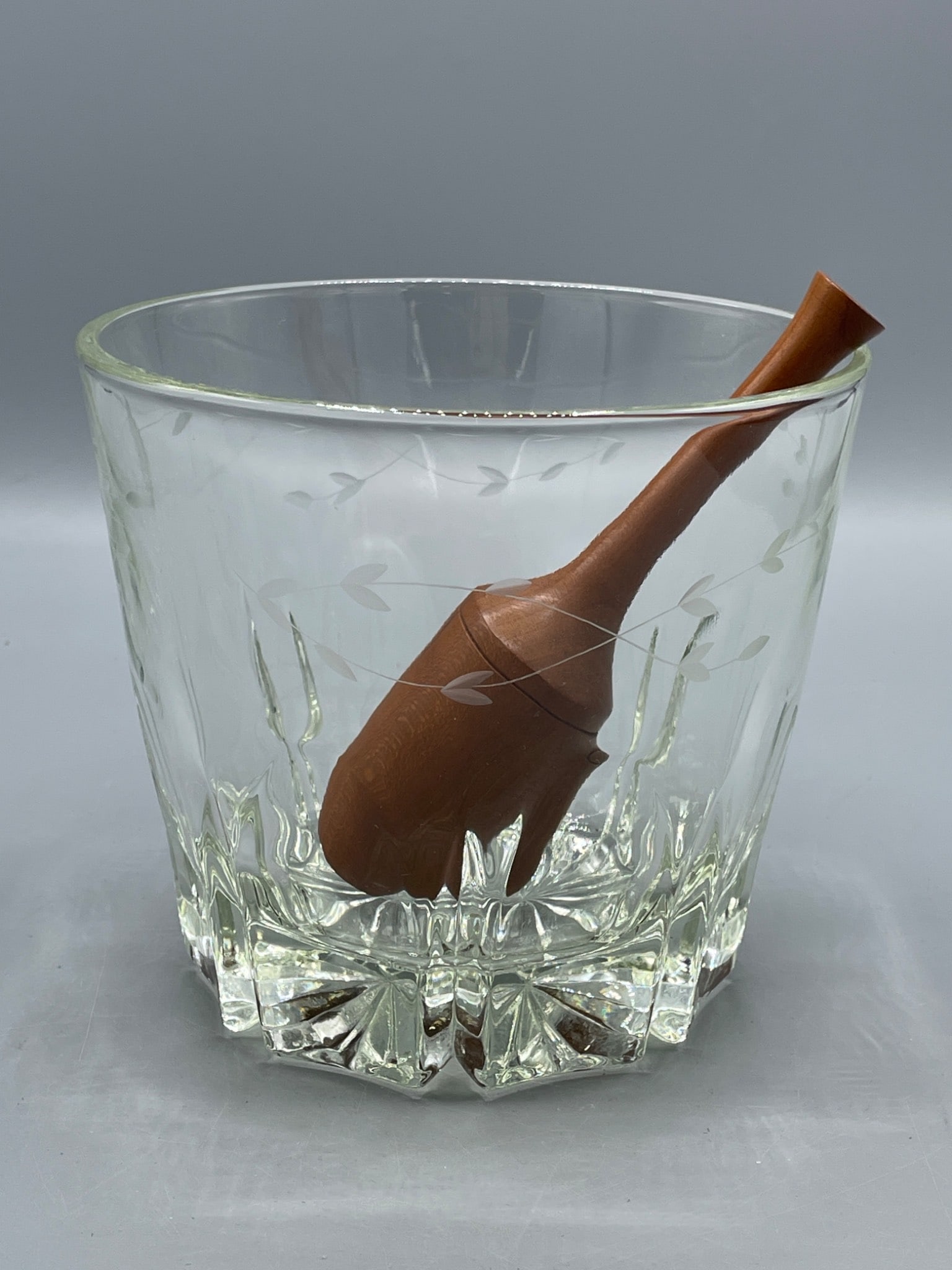 Clear Glass Bowl With Etched Design and Wooden Scoop: This lot includes a clear glass bowl featuring an etched vine pattern and a starburst design on the base. The set includes a wooden scoop. Dimensions approximately 4.5 inches in height and 5 inches