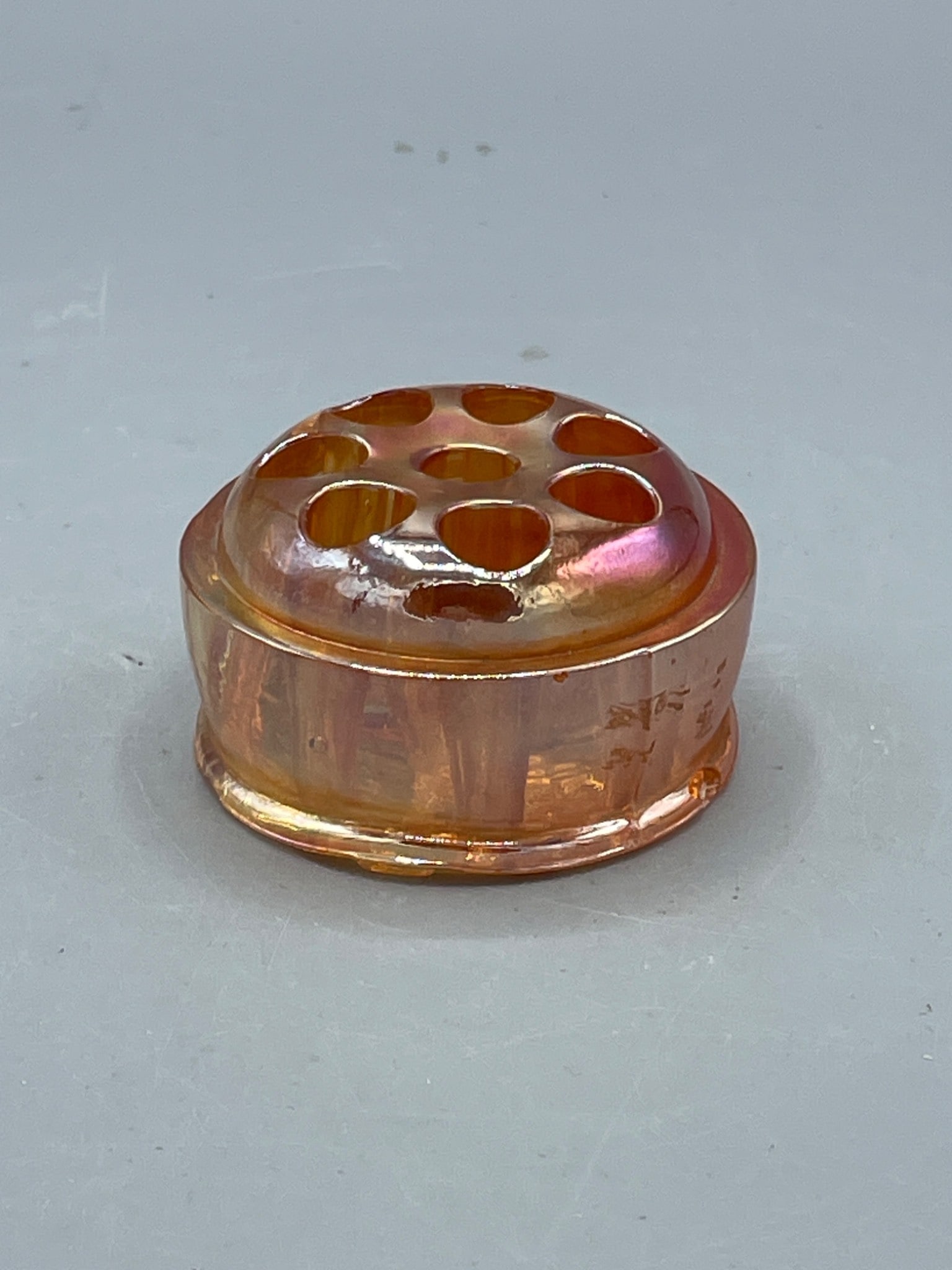 Iridescent flower frog: Glass flower frog featuring an iridescent finish, designed with seven circular slots for holding flowers. The piece measures approximately 2 inches tall and 3 inches in diameter. Condition appears