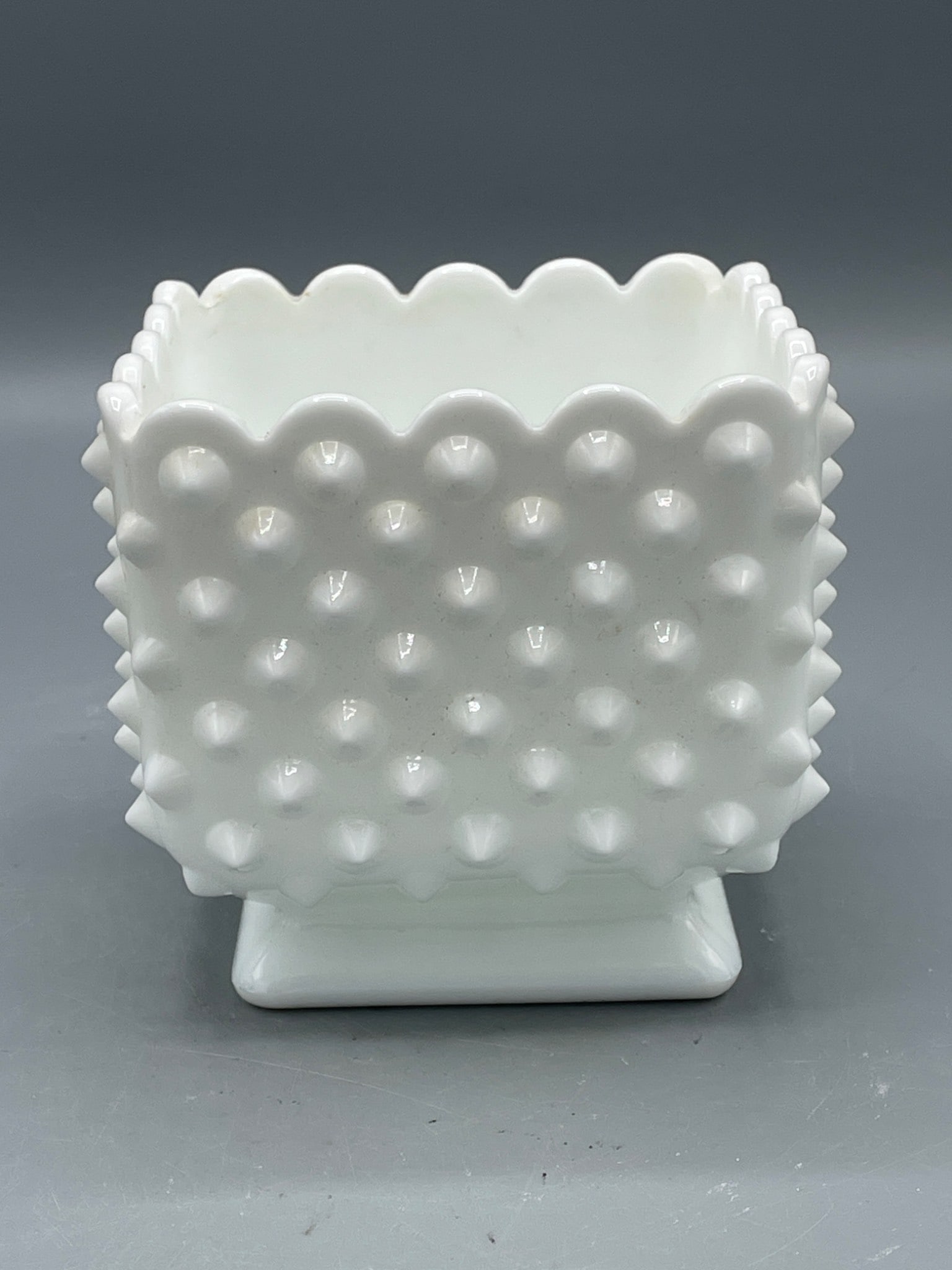 White Milk Glass Hobnail Square Pedestal Planter Bowl, Approx. 4 Inches Tall: This is a white milk glass hobnail square pedestal planter or bowl. The item features a scalloped rim and raised hobnail design on the exterior. The dimensions are approximately 4 inches in height,