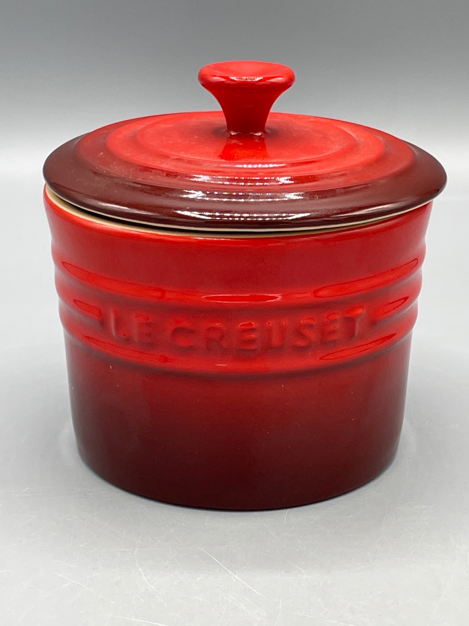 Le Creuset Medium Spice Jar with Lid, Cerise Red: Le Creuset medium spice jar in cerise red, featuring a matching stoneware lid. Manufactured in Thailand, item number 3625597. It measures approximately 4 inches in height. The underside has original
