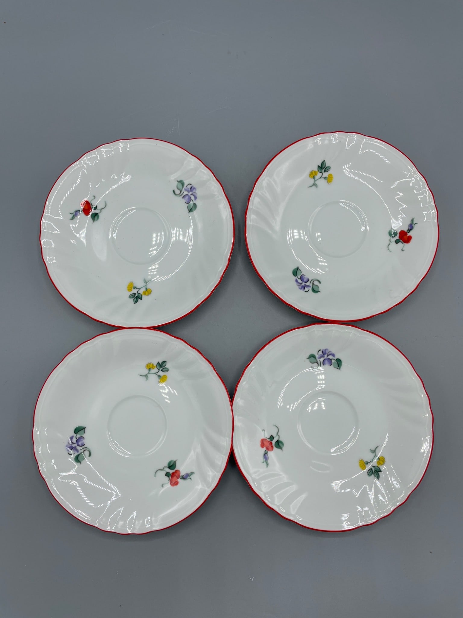 4 Fitz and Floyd Printemps Fine Porcelain Saucers, Made in Japan: 4 Fitz and Floyd 'Printemps' fine porcelain saucers. Manufactured in Japan, model 212, these saucers feature floral designs and a red rim. Each saucer measures approximately 6 inches in diameter, as s