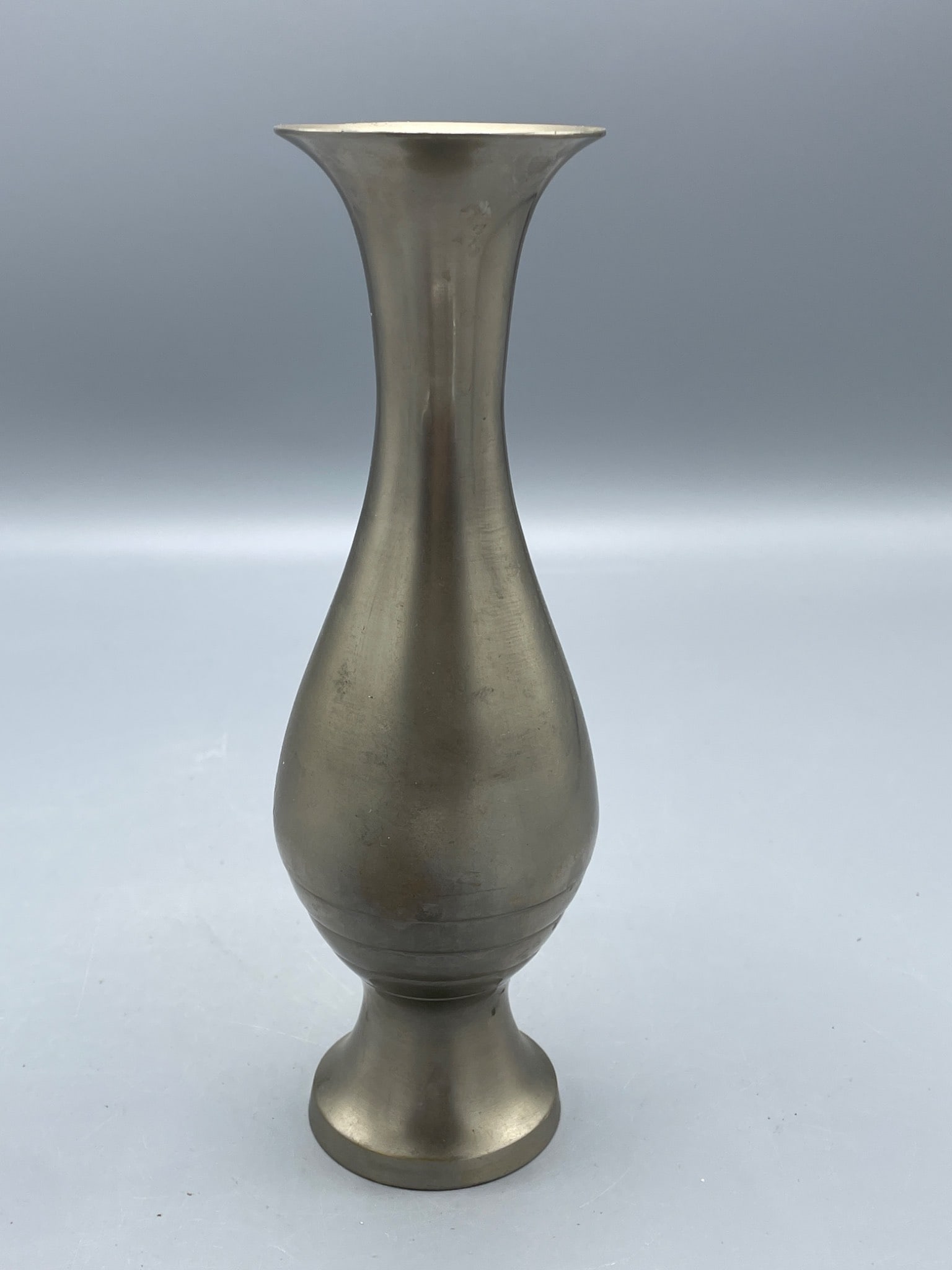 Metal Vase With Flared Rim and Pedestal Base, Approximately 8 Inches Tall: This is a metal vase with a flared rim and a rounded body tapering into a pedestal base. It stands approximately 8 inches tall and has a metallic finish consistent with brass or similar alloys. The