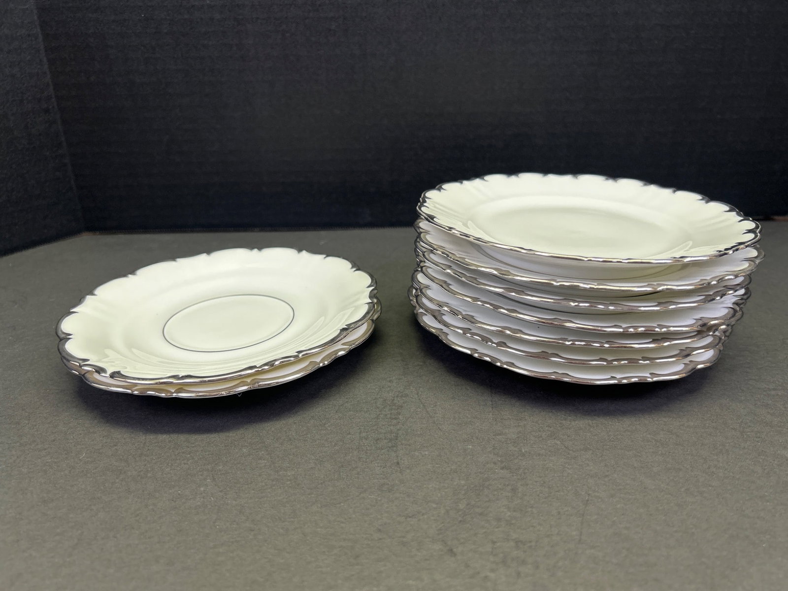 12 Schumann Arzberg Bavaria Dessert Plates With Silver Rim: This lot includes a set of 12 dessert plates manufactured by Schumann Arzberg, Bavaria. The plates feature scalloped edges with a silver rim and measure 5.25 inches in diameter. The backstamp identifi