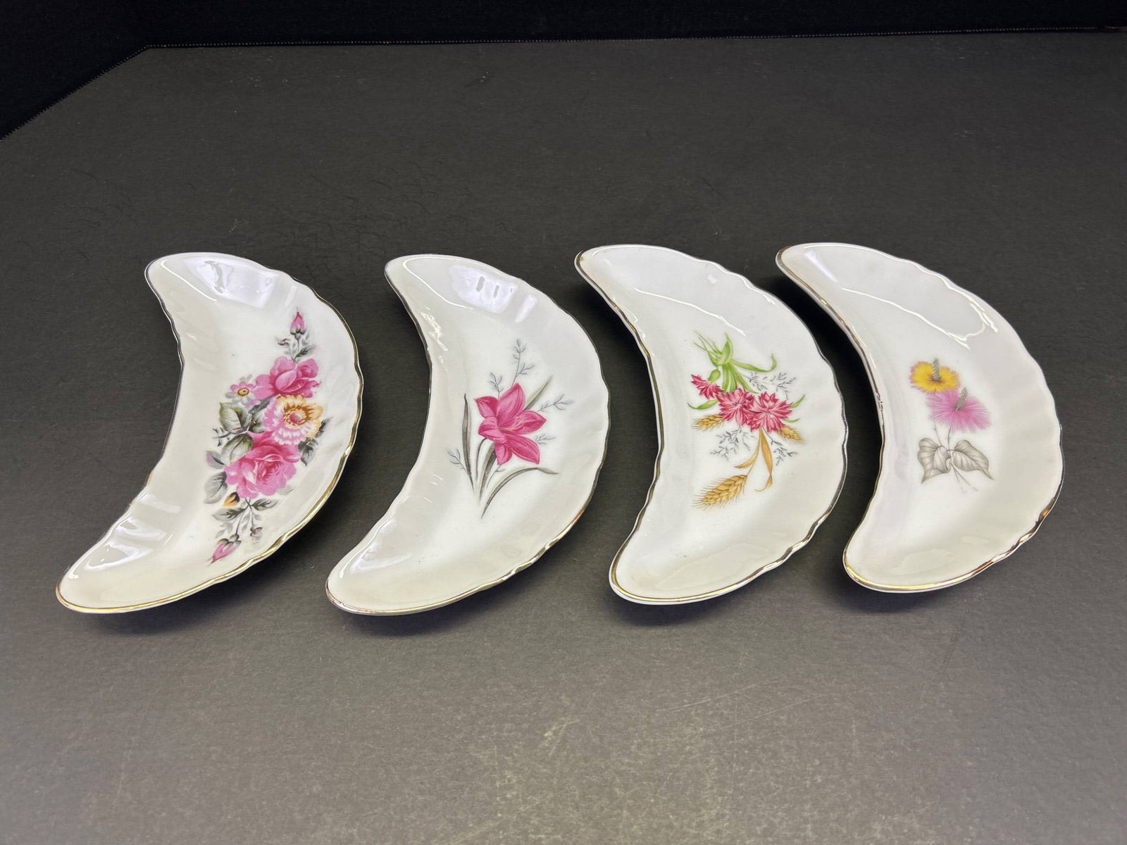 4 Royal Crown Derby Decorative Bone China Crescent Salad Plates: This is a set of 4 Royal Crown Derby bone china crescent salad plates. Each plate features a floral design with gold trim and includes the Royal Crown Derby mark on the bottom. The plates measure