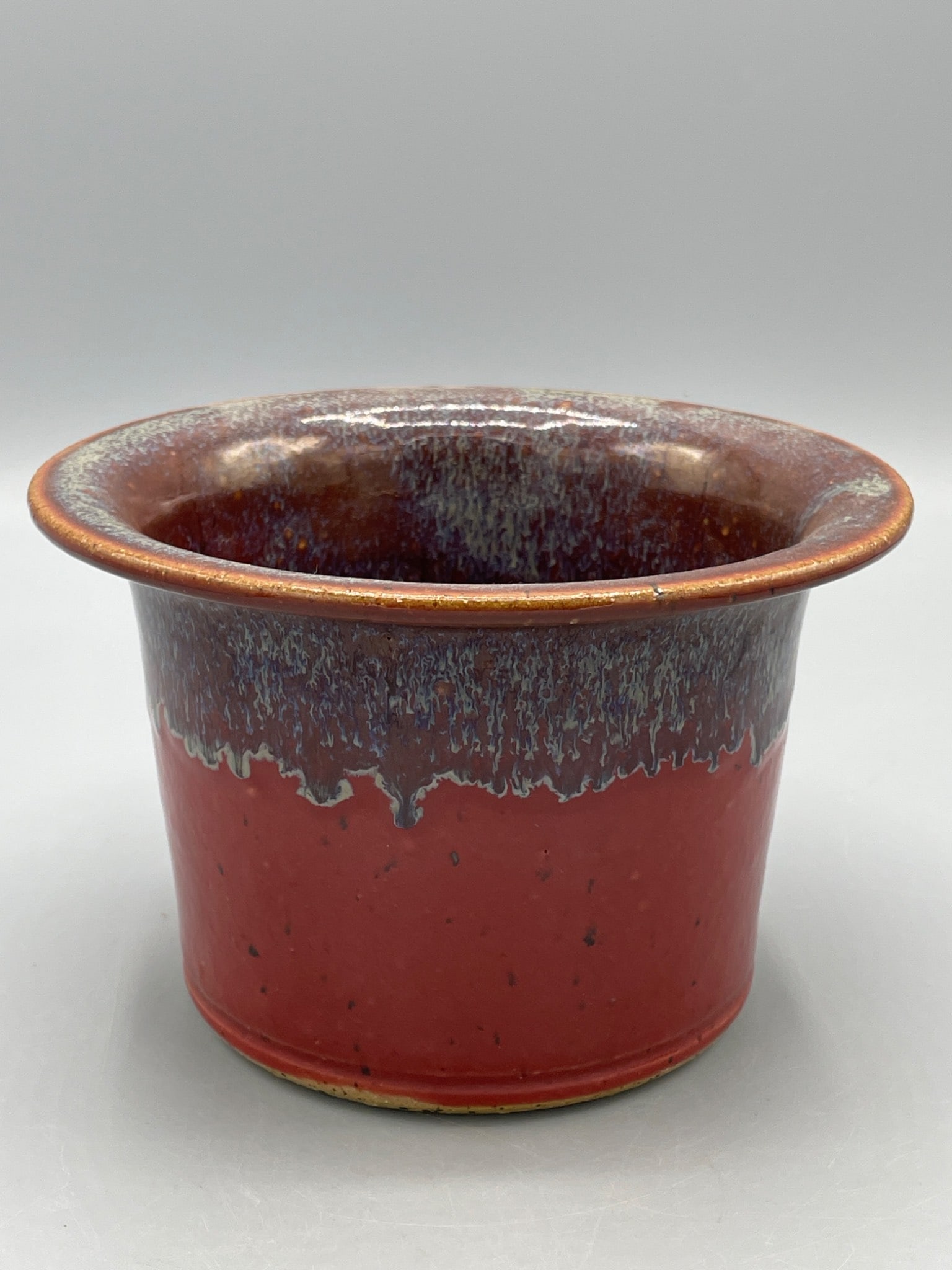 Handcrafted Ceramic Bowl with Red and Blue Glaze: This is a handcrafted ceramic bowl featuring a dual-tone red and blue glaze. The base has an inscription with the text â€˜Triple C Jesus Saves.â€™ The item stands
