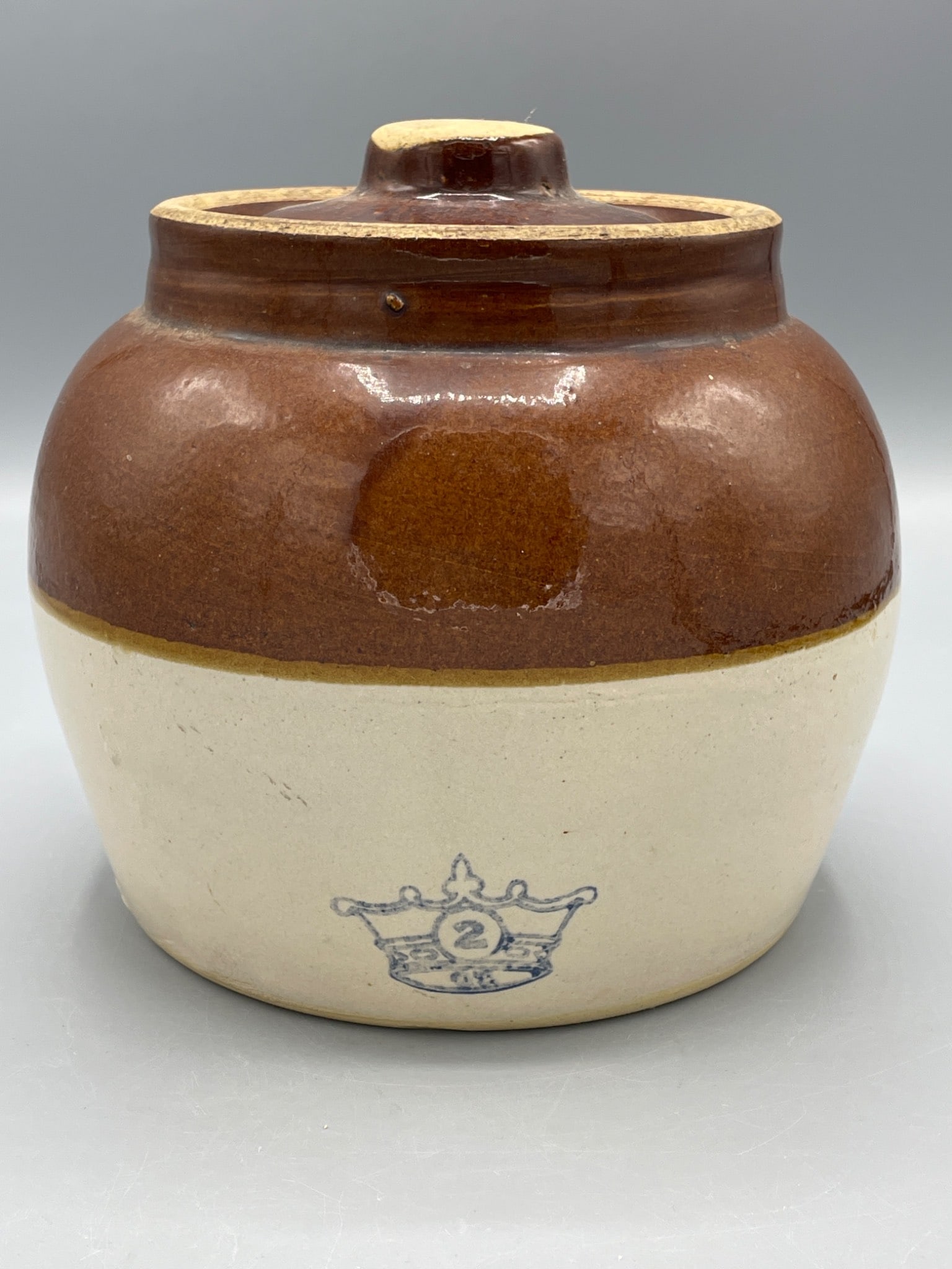 Two-Gallon Stoneware Crock With Lid and Crown Stamp, Marked â€˜USAâ€͐: This brown and beige stoneware crock has a two-gallon capacity, marked by a crown stamp with the number â€˜2â€™ on the front. It includes a matching lid and a single