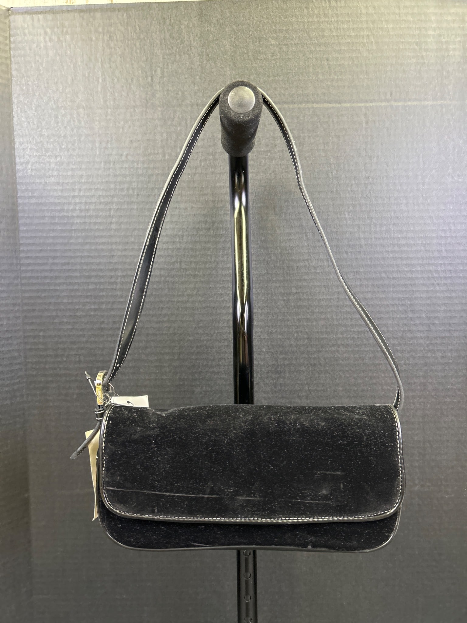 Black Suede Shoulder Bag with Magnetic Closure: This is a black suede shoulder bag featuring a magnetic snap closure. The bag comes with a leather strap and internal compartments. The included tags remain attached, suggesting minimal prior use.