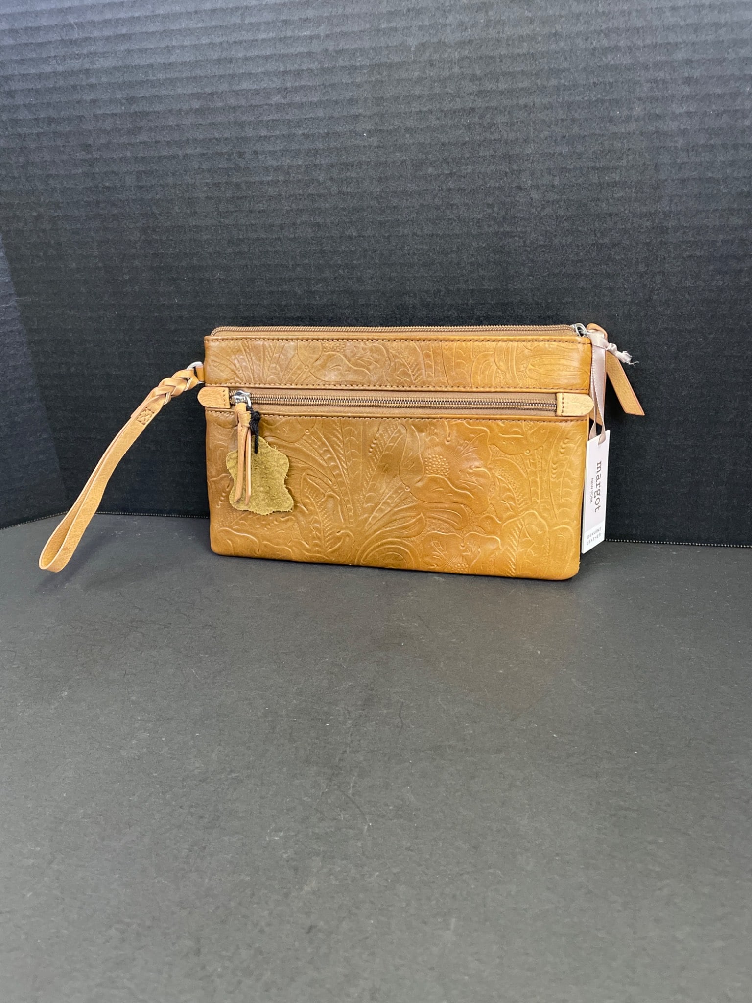 Margot New York Genuine Leather Wristlet With Embossed Design: This is a Margot New York wristlet crafted from genuine leather, featuring an embossed design. The wristlet includes a convenient wrist strap, a zippered main compartment, and interior dividers for