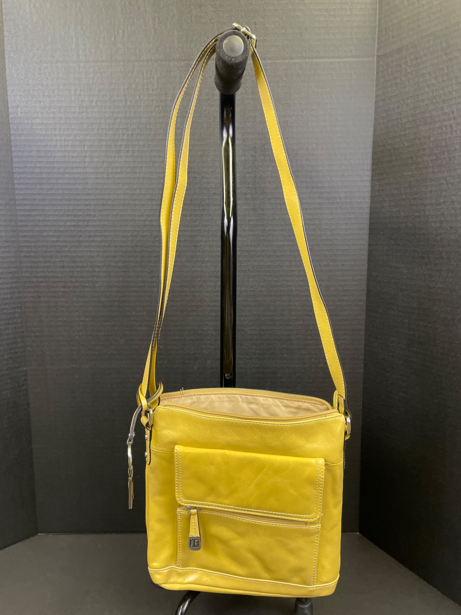 Yellow Crossbody Bag with Multiple Compartments and Adjustable Strap: Yellow crossbody bag featuring an adjustable strap, external front pocket with zipper closure, large zippered main compartment, and interior pocket organization for cards and small items. The bag