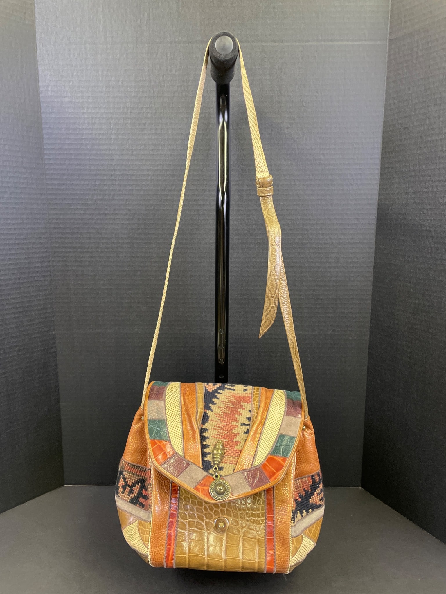 Preowned Multicolor Shoulder Purse With Adjustable Strap: Preowned shoulder purse featuring multicolor design with an adjustable strap. Exterior includes a mix of textured and patterned fabric, with a secure snap closure. Interior features multiple