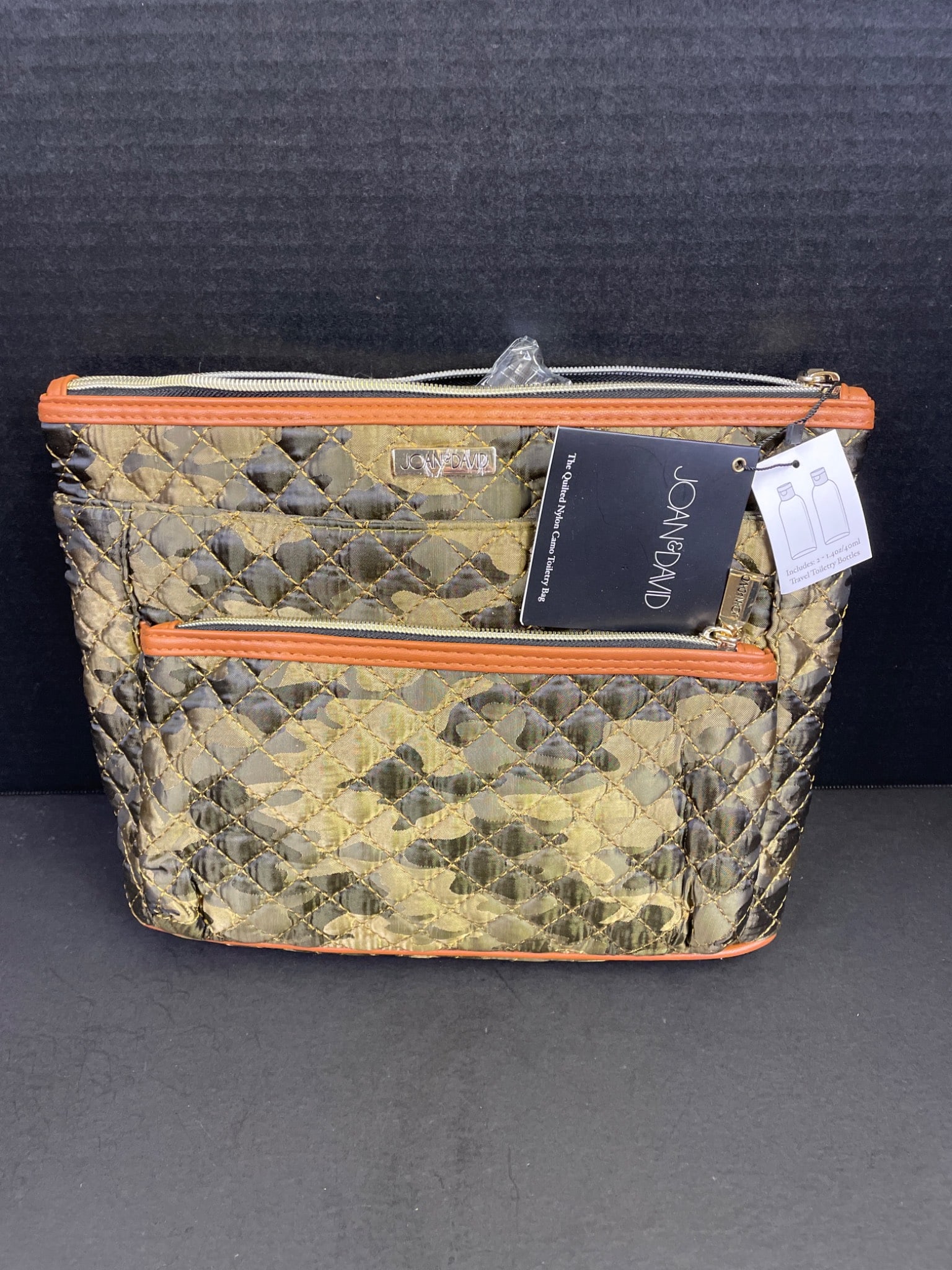 Joan & David Quilted Nylon Camouflage Cano Toiletry Bag: Joan & David Quilted Nylon Cano Toiletry Bag in camouflage design. Features quilted nylon construction, zip closure, and a front pocket. Orange trim accents provide stylish detailing. Includes