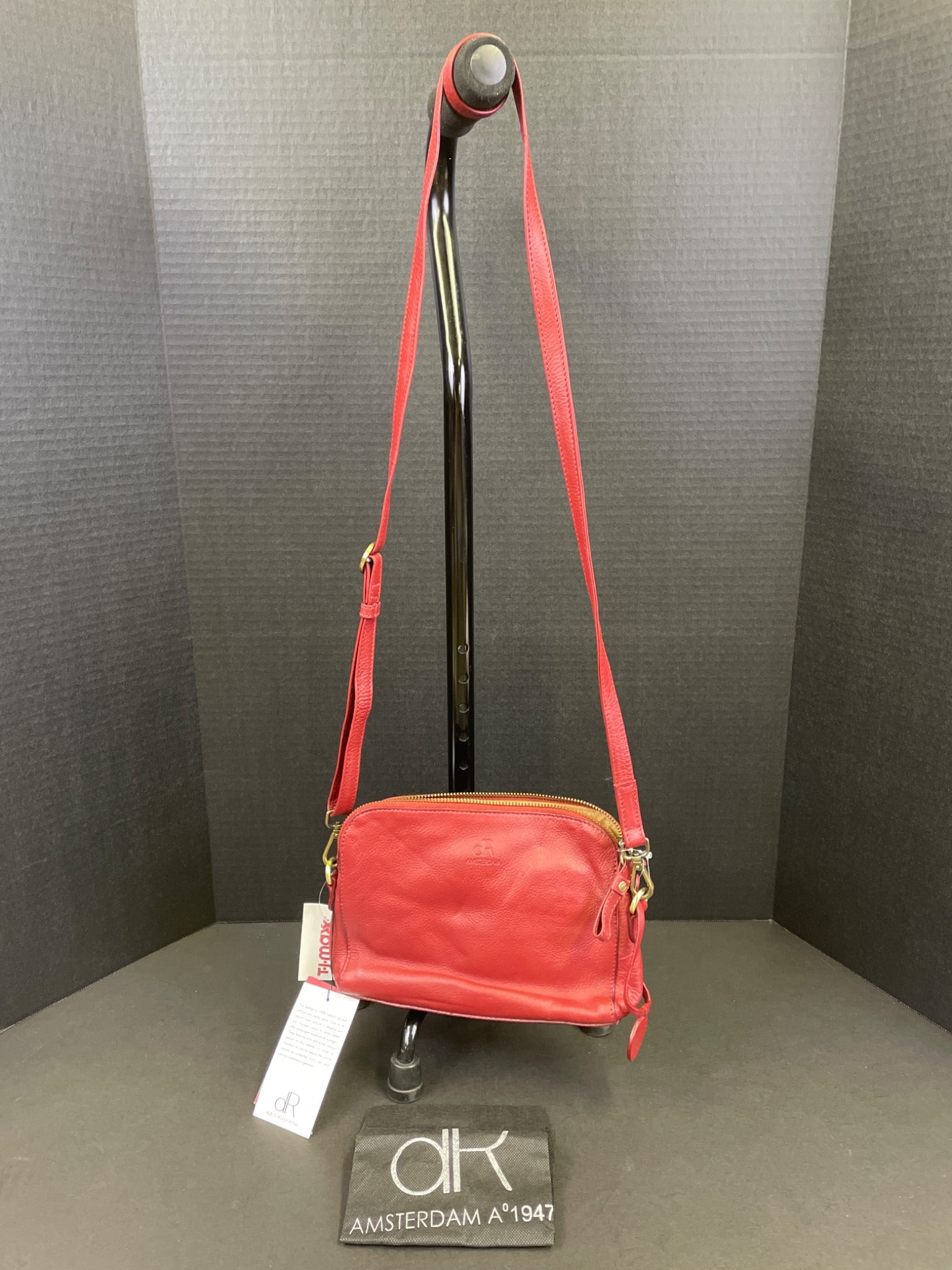 DR Amsterdam 1947 Genuine Leather Small Shoulder Bag with Tags: DR Amsterdam small shoulder bag, crafted from genuine red leather. Features a zippered top closure and gold-tone hardware. Interior includes multiple compartments and slots for organization. Comes wit