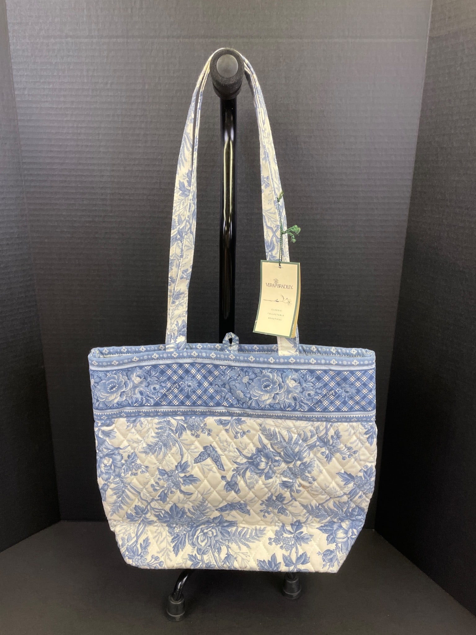 Vera Bradley Quilted Blue and White Floral Tote With Original Tag: This Vera Bradley quilted tote bag features a blue and white floral pattern. The bag includes two handles, a zipper closure, and interior compartments for organization. The original tag is attached,