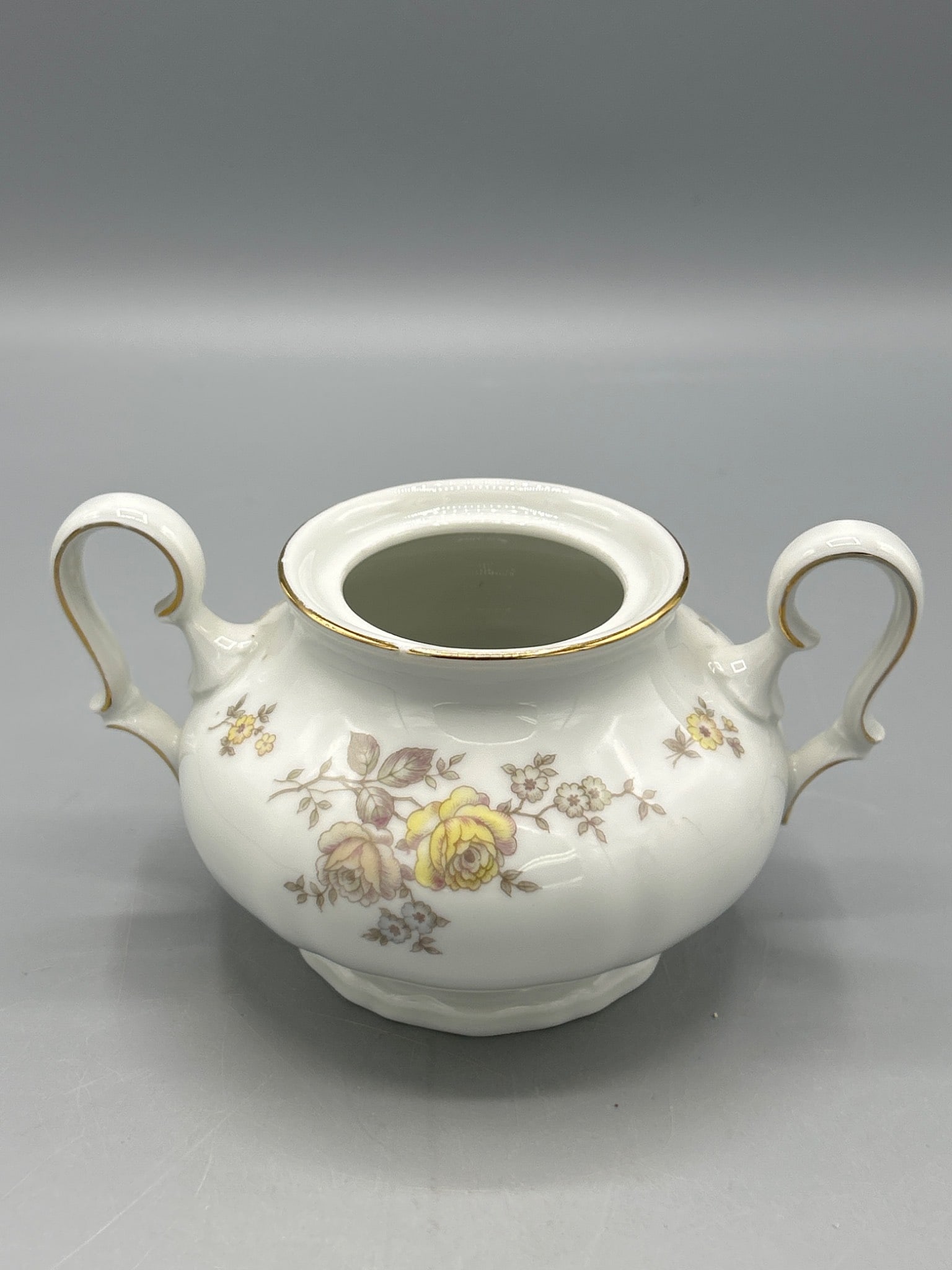 Johann Haviland Bavaria Germany Chippendale Pattern China Sugar Bowl with Floral Design: A two-handled china sugar bowl from Johann Haviland, crafted in Bavaria, Germany, in the Chippendale pattern. It features a white base with yellow floral decals and gold trim. The base is stamped