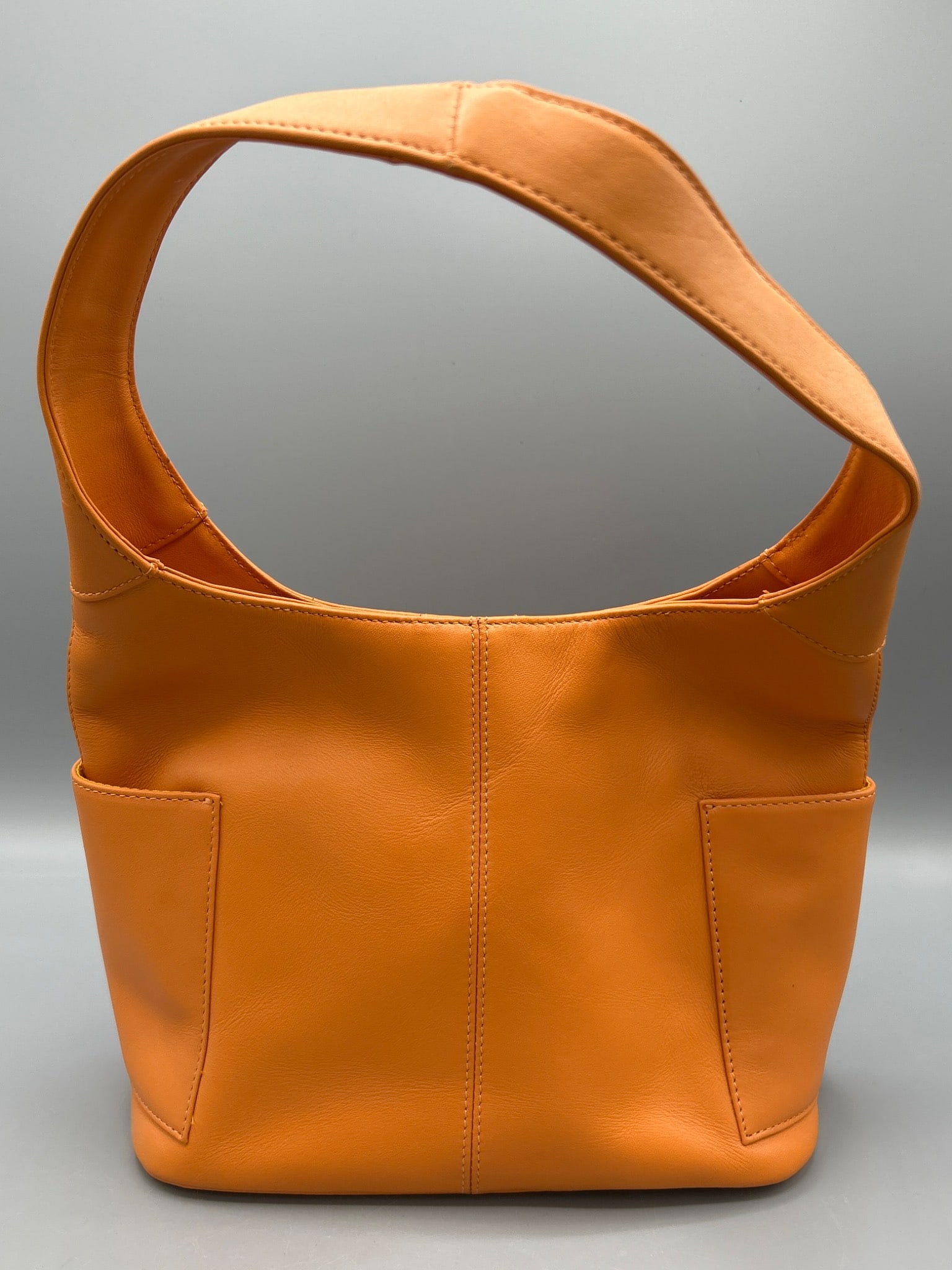 Preston & York Orange Leather Shoulder Bag With External Pockets: This is a Preston & York leather shoulder bag in bright orange, featuring two external pockets and a snap-closure mechanism. The interior includes multiple compartments for organization. The strap is