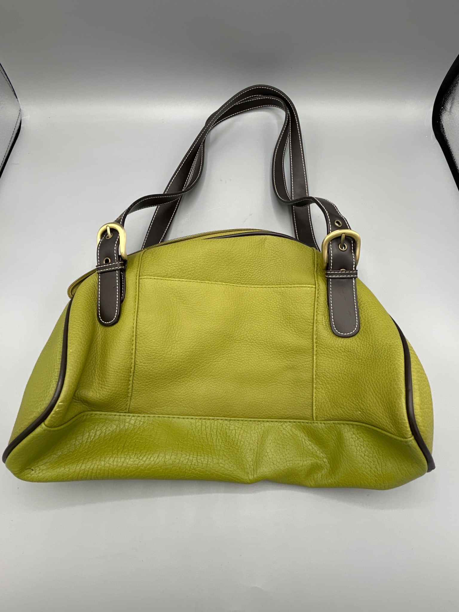 Great American Leatherworks Green Leather Handbag With Brown Straps: This handbag by Great American Leatherworks features a green leather construction with brown dual shoulder straps and gold-tone buckle accents. It includes an interior pocket, a zipper closure, and a