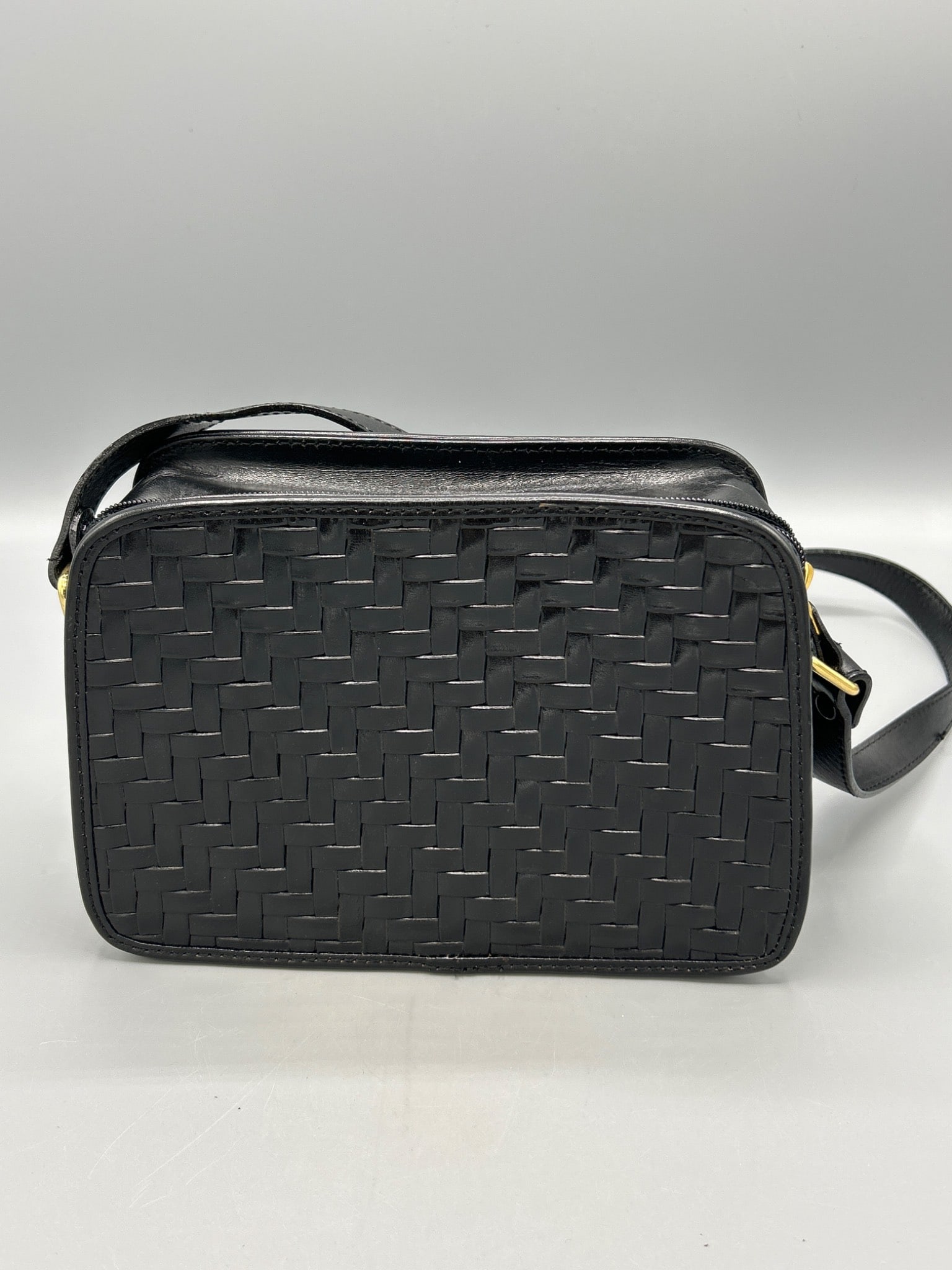 Black Valerie Stevens Woven Leather Crossbody Bag with Adjustable Strap: This bag by Valerie Stevens features a woven leather front and back design, an adjustable shoulder strap, and a zippered main compartment. The branding is embossed on a gold-tone interior plate. The