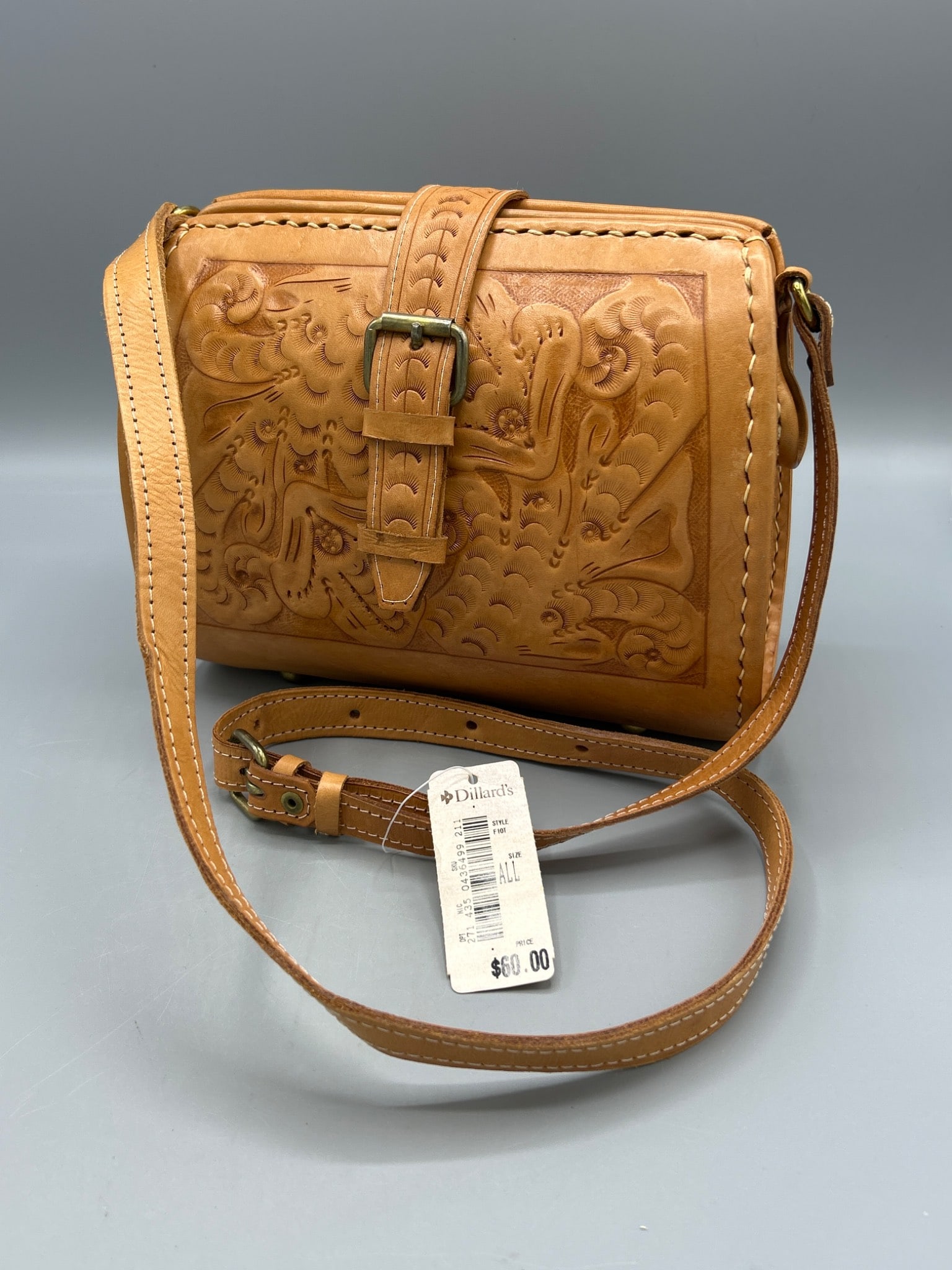 Leather Handbag With Tooled Design and Adjustable Strap, Made in Paraguay: This is a leather handbag featuring an intricate tooled design and adjustable strap. It has a top buckle closure, a patterned interior lining, and a tag marked 'Made in Paraguay' affixed inside. The l
