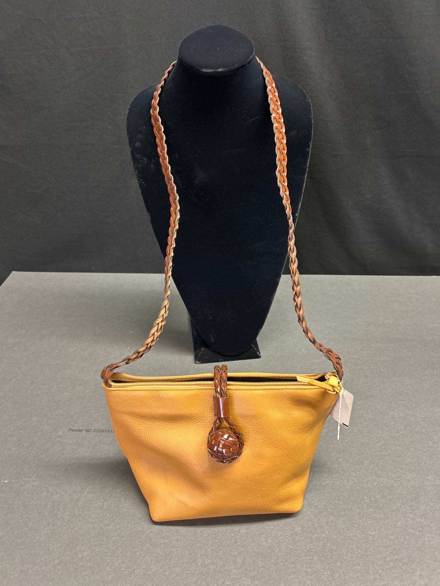 LJS Collection Leather Shoulder Bag With Braided Strap and Zipper Closure: This item is a leather shoulder bag from LJS Collection. It features a braided strap, a decorative closure, and a top zipper to secure contents. The bag is lined with a black interior and includes an