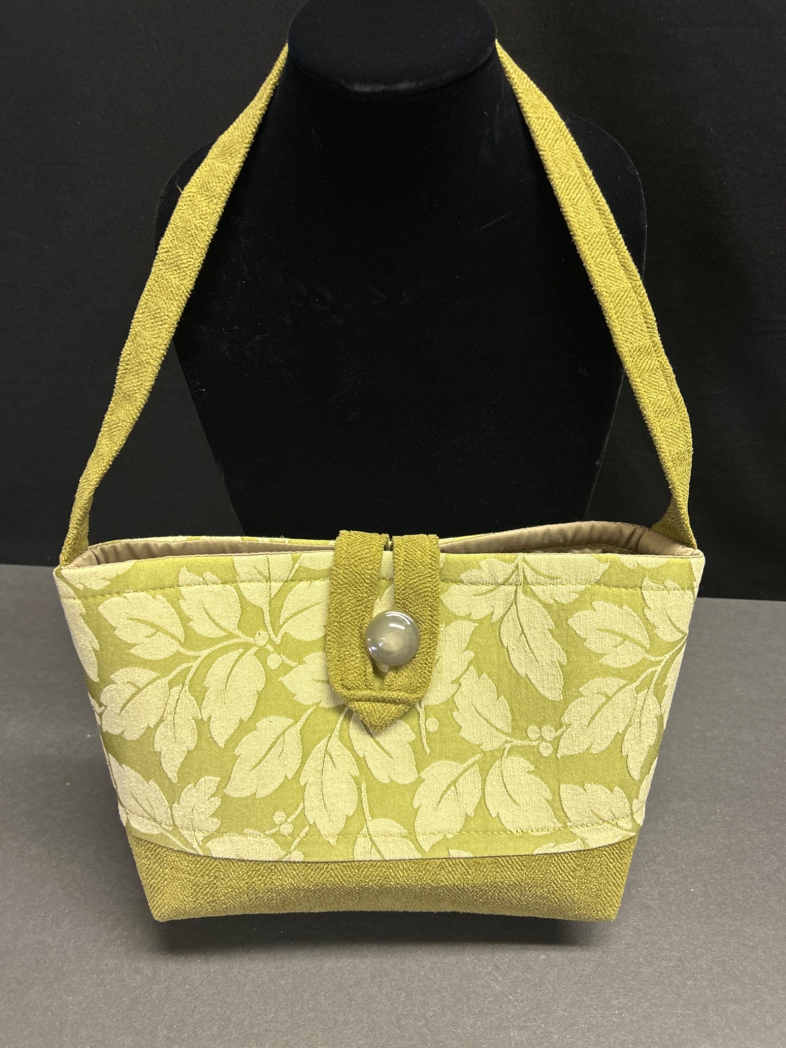Green Fabric Handbag with Leaf Pattern from EverSewEnglish, LLC: A handcrafted fabric handbag produced by EverSewEnglish, LLC, Fredericksburg, VA, as indicated on the interior label. The handbag features a green exterior with a leaf pattern, a single snap-button