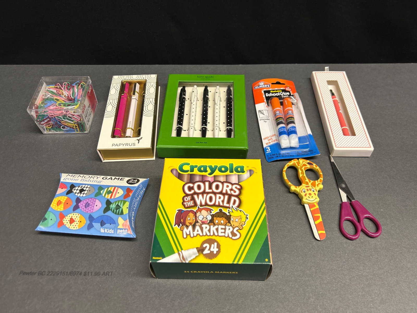 Stationery and Art Supplies Including Pens, Markers, and Scissors: This lot includes a selection of stationery and art supplies, including a Crayola Colors of the World 24-marker set, a Kate Spade ink pen set (5 pieces), a Papyrus 3-pen set, a pink boxed pen, a pack