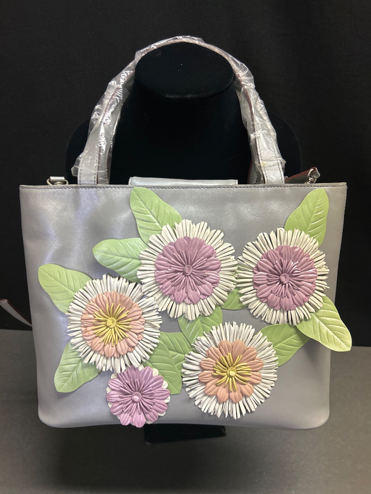 Accents by Sheryl Genuine Leather Handbag With Floral Applique: This is a genuine leather handbag from Accents by Sheryl, featuring floral applique detailing on the front. The bag includes dual handles with protective wrapping, a detachable strap, and a zippered