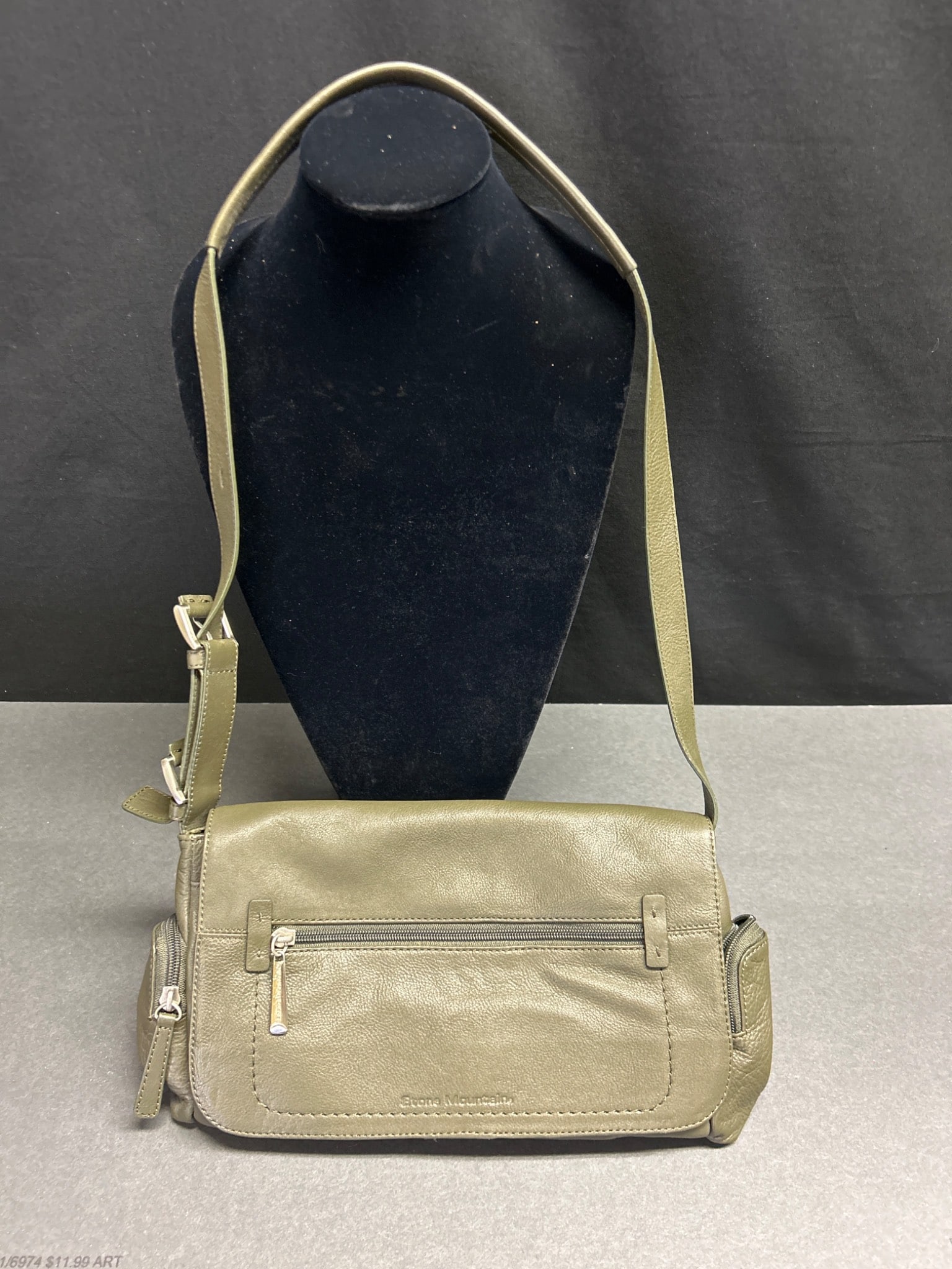Stone Mountain Leather Crossbody Bag With Adjustable Strap: Stone Mountain leather crossbody bag in an olive-green color, featuring an adjustable strap and multiple compartments, including a zippered front pocket. Interior includes fabric lining and zippered