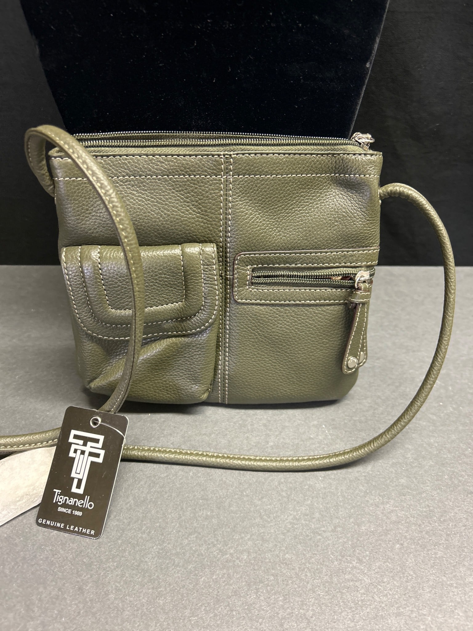 Tignanello Genuine Leather Crossbody Bag with Zipper Compartments: Tignanello crossbody bag made from genuine leather in olive green. Features a front pocket with snap closure, a zippered pocket, and additional compartments for organization. Includes a top zipper