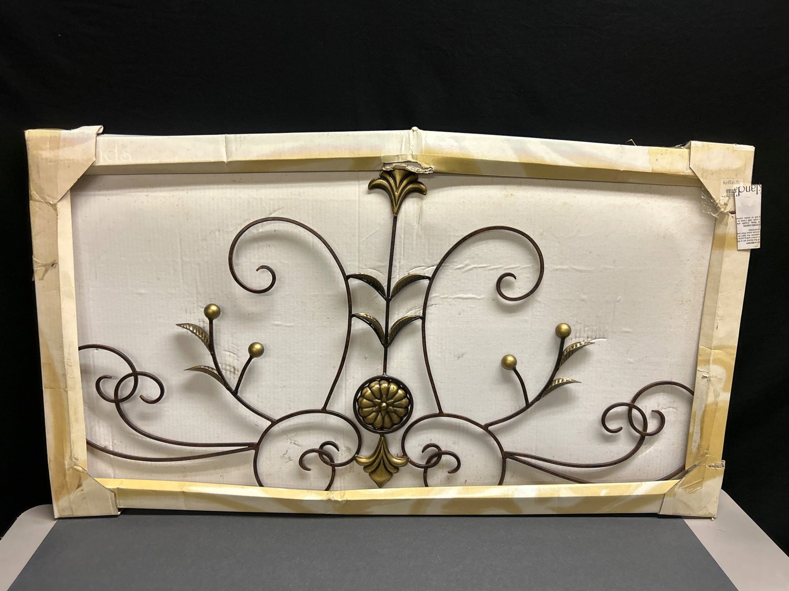 Kirkland's Decorative Wall Scroll Panel with Original Packaging: This item is a decorative metal wall scroll panel distributed by Kirkland's Stores, Inc. (Item DPP 065910). It features a wrought iron design with intricate swirls and floral details. The item is