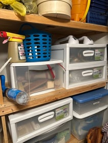 Utility shelving unit with assorted storage bins, organizers, cleaning supplies, spotlight, and