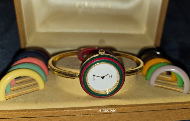 Gucci 1100- I, yellow gold, bangle style watch with twelve different colored, hard plastic resin: For sale is an iconic Gucci 1100- I, yellow gold, bangle style watch with twelve different colored, hard plastic resin bands you can add to the white watch face to change its look! It comes in its ori