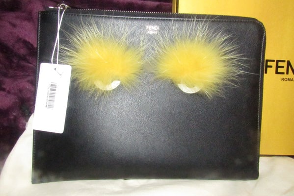 Fendi NIB w tags, black leather 'Monster' clutch w yellow fur lashes and zip around closure: For sale is a Fendi NIB w tags, black leather 'Monster' clutch w yellow fur lashes and zip around closure! This is a great style for going out in a RARE, iconic Fendi design! The bag is a ra
