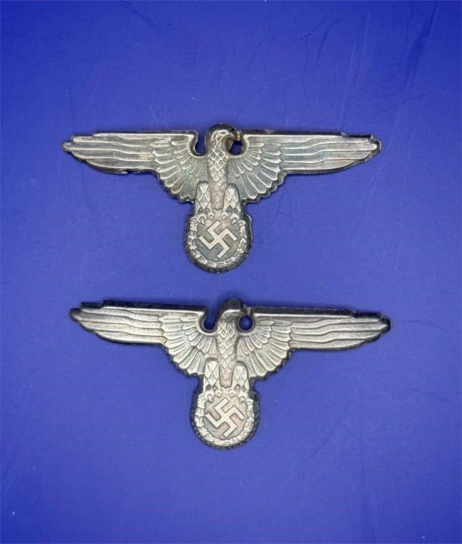 M1/72 SS Visor Cap Eagle (2piece): Dimensions: 3in x 1inConstructed of cupal, the obverse consisting of an SS-style German national eagle clutching a wreathed mobile swastika, the reverse marked with a Reichszeugmeisterei (RZM) logo an