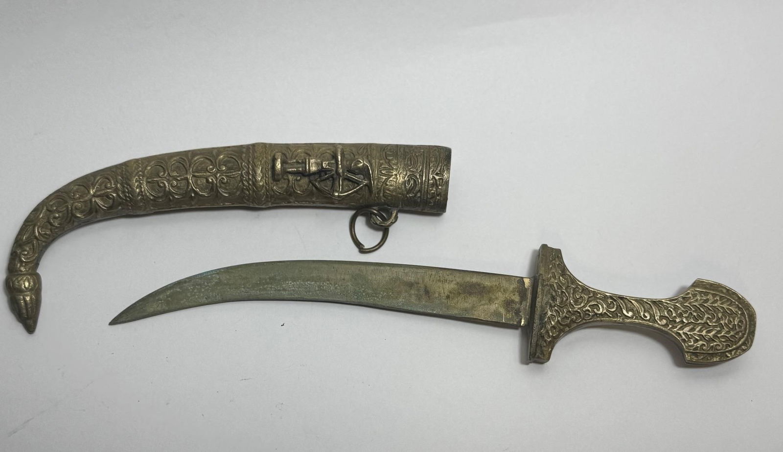 Brass-Toned Dagger Souvenir: Dimensions: 13in x 4in x 1.5inDecorated curved dagger and its matching scabbard, likely made entirely of brass or a brass-toned metal alloy. This style is often decorative or ceremonial, heavily influ