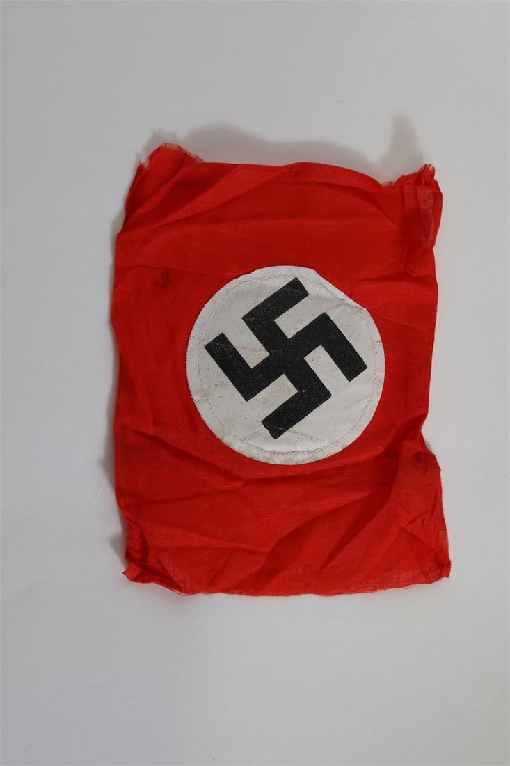 WWll German Party Armband: Two sided red cloth armband featuring a white circular roundel with a black angled swastika at the center. Constructed of woven fabric with finished edges. Measures approximately 7.5 × 6.7 inches.