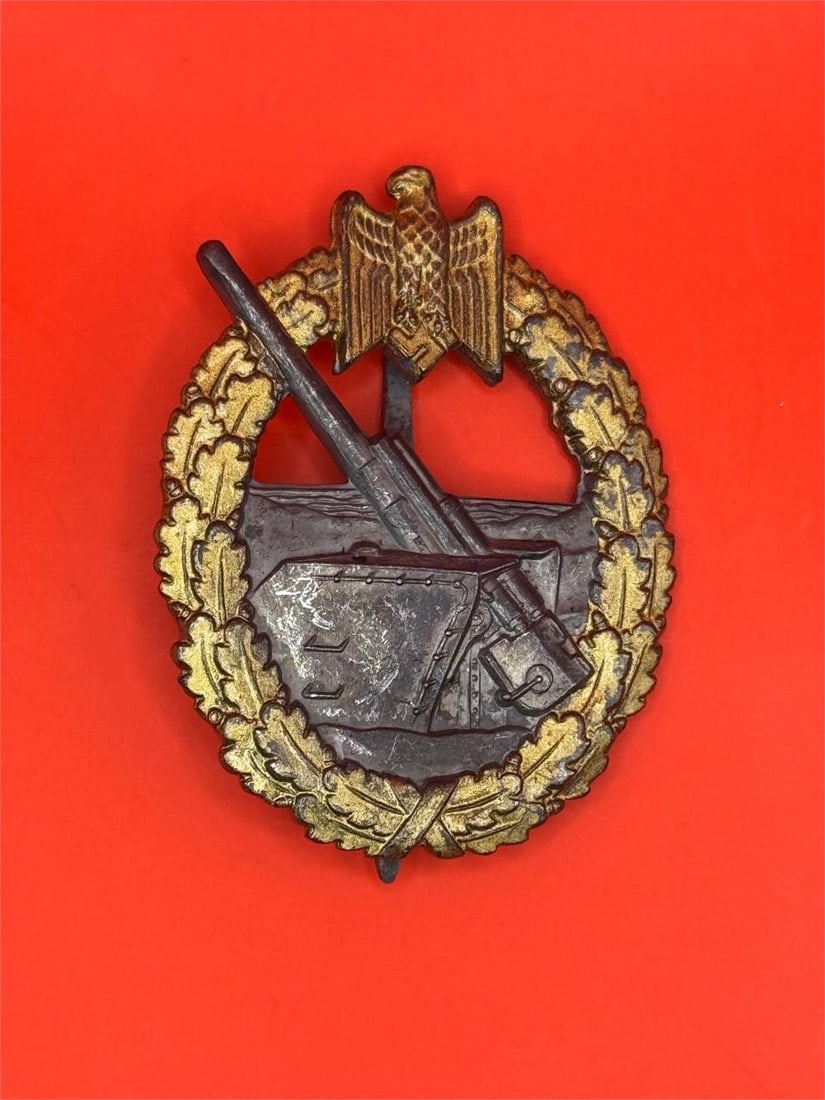 Kriegsmarine Coastal Artillery Badge: Dimensions: 2in x 1.5inThe badge features an eagle gripping a swastika atop an oak leaf wreath, with a depiction of a coastal artillery gun inside the wreath. Award Criteria: The award was given to cr