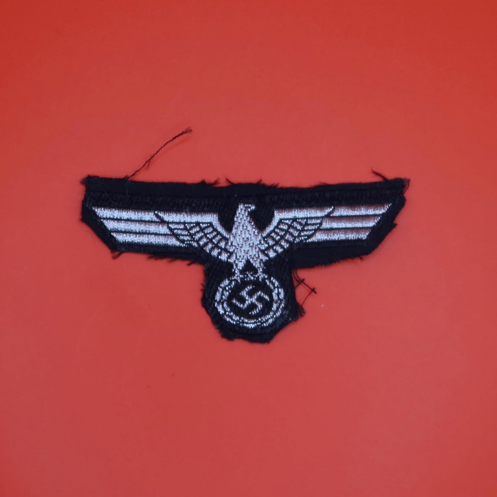 WWII Panzer Side Cap Eagle: German Army Panzer troops side cap eagle in the smaller size, BeVo-woven construction. Features a stylized national eagle in fine machine weave with crisp detail. Removed-from-uniform condition, showi