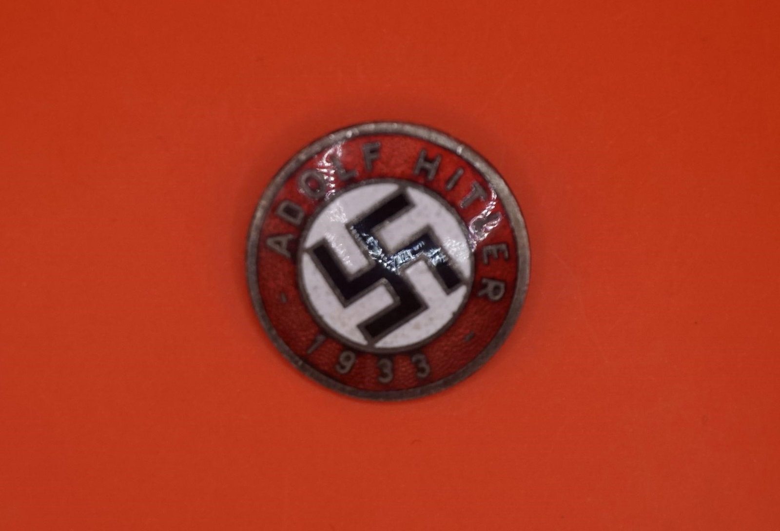 WWII NSDAP ENAMEL PARTY LAPEL BADGE.: A circular lapel badge, an earlier type with 'Adolf Hitler 1933' to the border with red ground and swastika to the center. RZM and M1/128. 2.5cm.