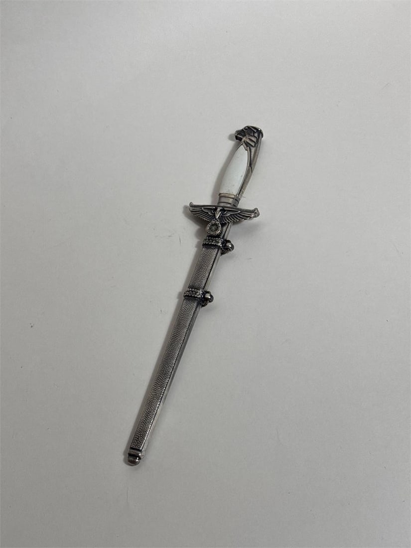 WWII GERMAN WWII DIPLOMATIC MINIATURE DAGGER: Rare WWII German miniature diplomatic dagger featuring a straight steel blade, Reichsadler pommel, and eagle-form crossguard with swastika. Complete with metal sheath and two belt loop rings. With a l