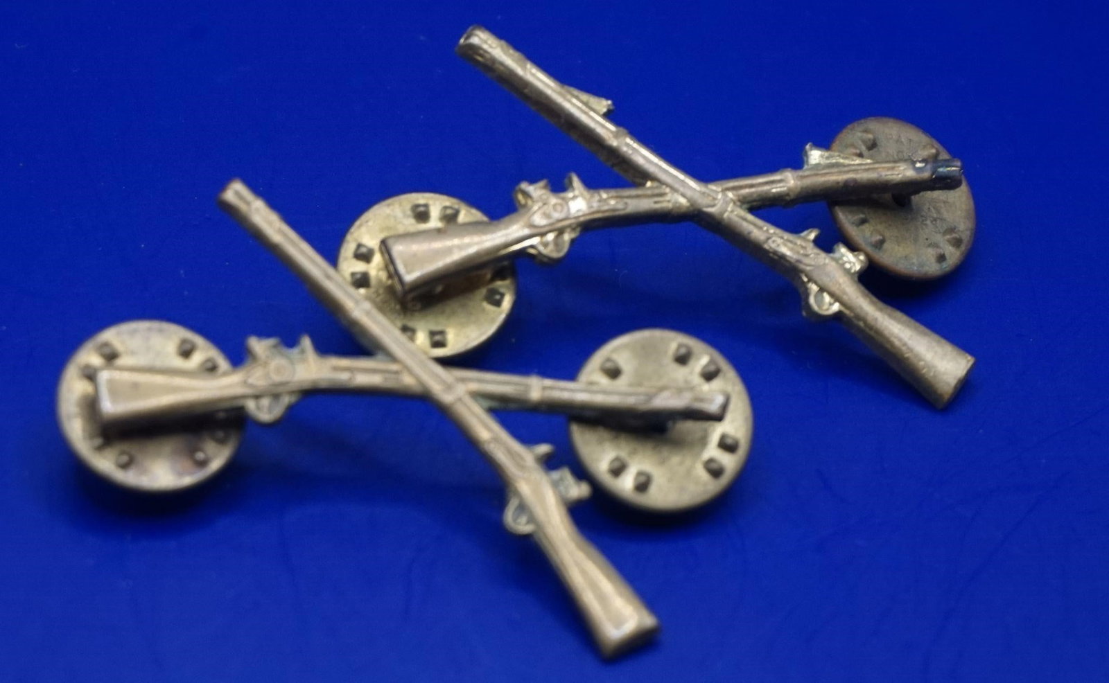 WWII US Army Infantry Officer's Branch Insignia: These are U.S. Army Infantry Officer's branch insignia, featuring the crossed rifles symbol used to denote the infantry branch. The insignia are often associated with the World War II era. Officers ty