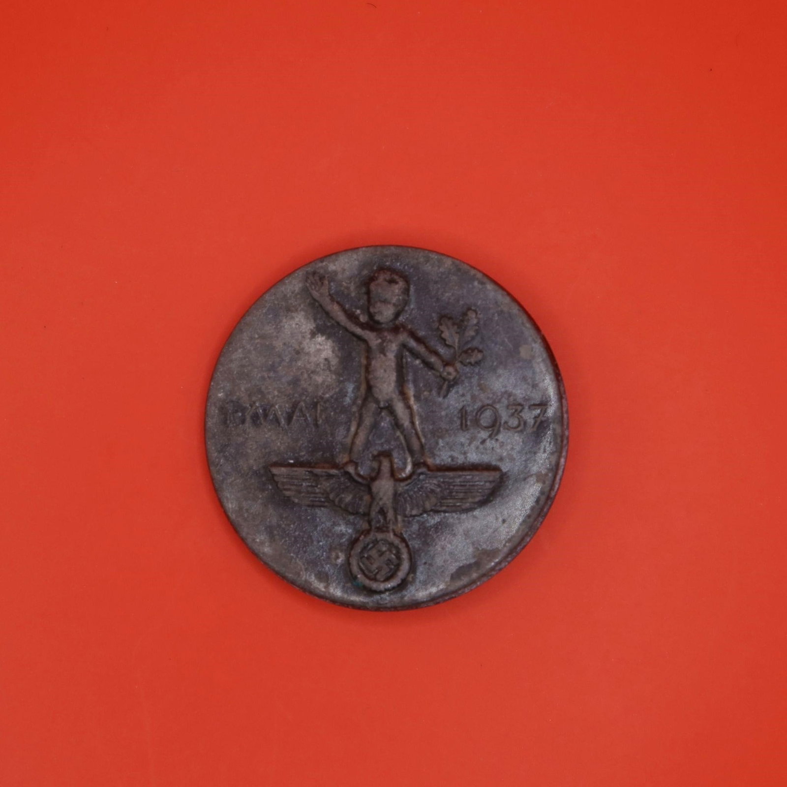 German May Day "Tag der Arbeit" Tinnie: A 1937 May Day commemorative badge showing a child holding an oak branch standing above the national emblem. Issued for the annual "Tag der Arbeit" celebration. The reverse carries the maker mark R. S