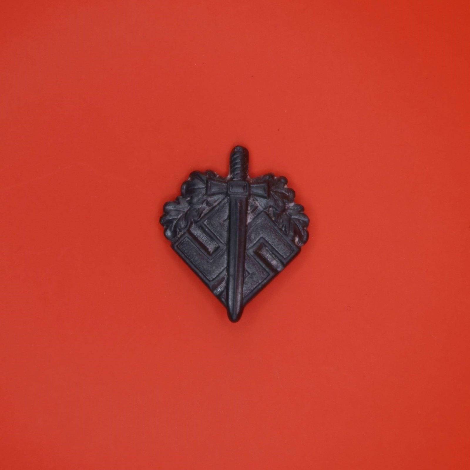 NSKOV Donation Pin (WWII Era): A small aluminum lapel pin issued by the NSKOV, an organization that supported wounded German veterans. The front shows a sword laid over a swastika with oak leaves around the upper portion. The rever