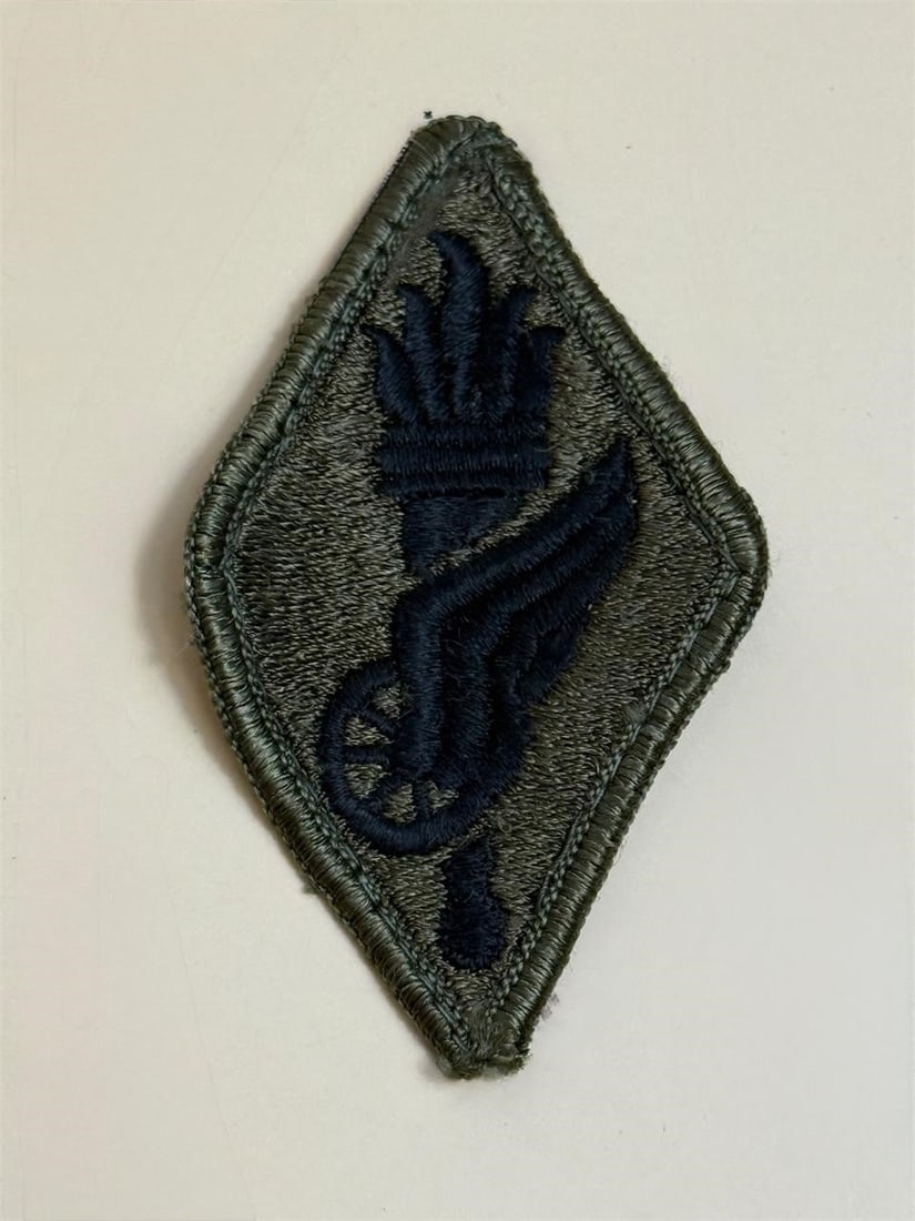 Subdued U.S. Army Transportation School Patch: Subdued U.S. Army Transportation School shoulder sleeve insignia patch. The patch features a winged wheel surmounted on a flaming torch, which is the branch insignia of the Transportation Corps. The