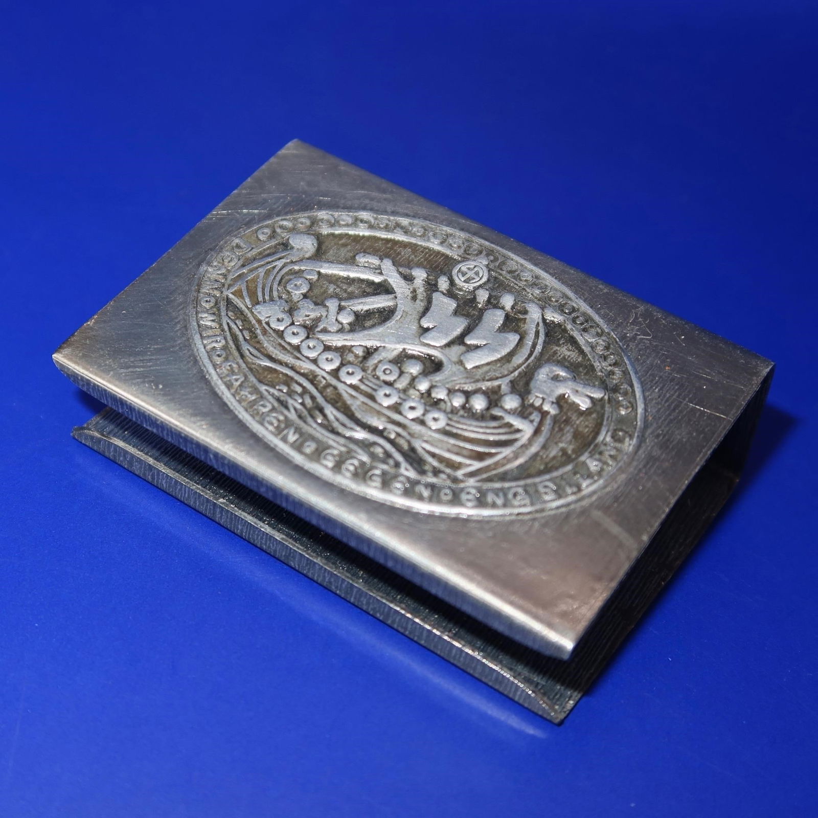Waffen-SS Wiking Badge & Matchbook Cover: Enamel Waffen-SS Division Wiking badge depicting a Viking ship with large SS runes on the sail above a German inscription, reverse marked Ges. Gesch. Accompanied by a matching Wiking matchbook cover