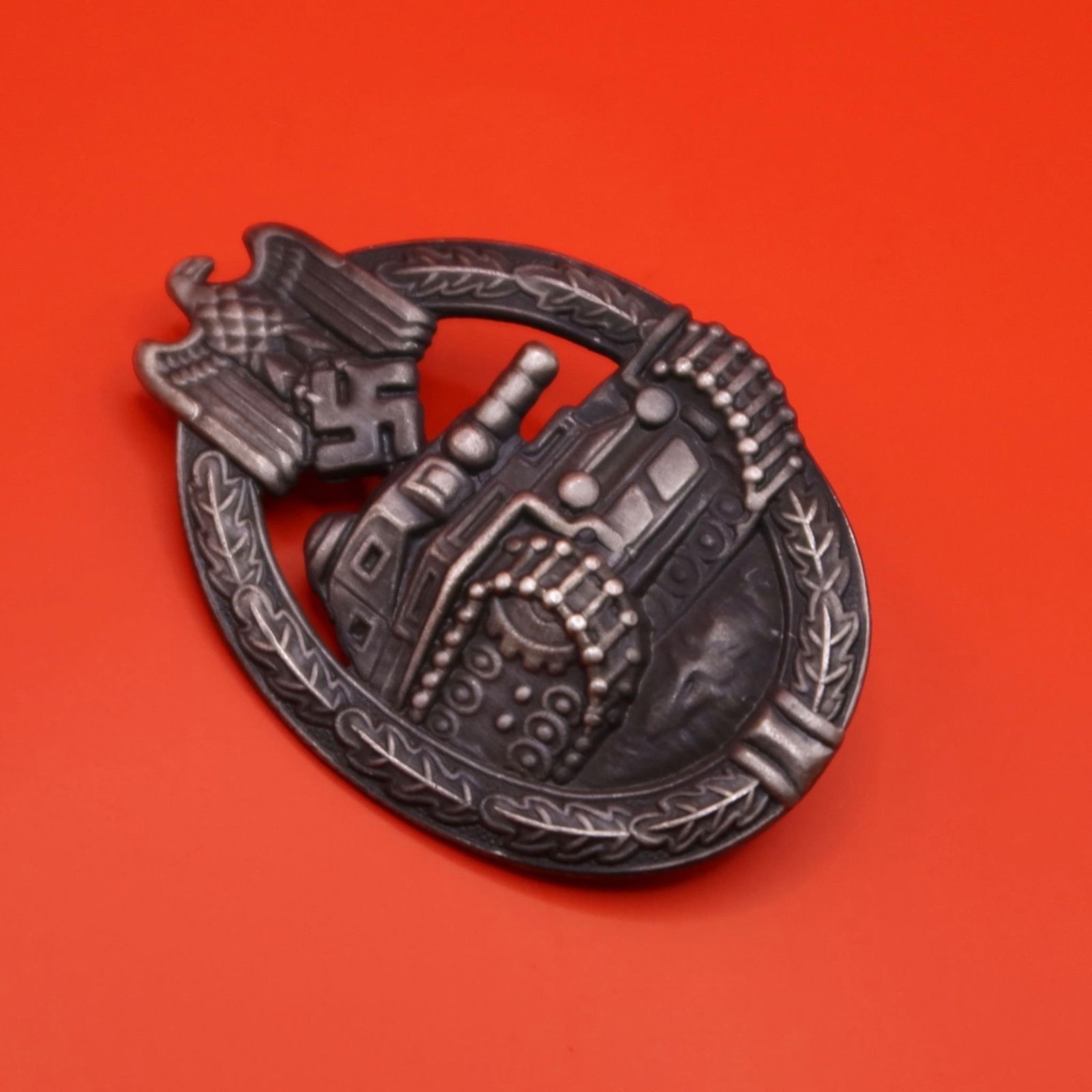 WWII German Panzer Badge (Silver Grade): Oval zinc Panzer Badge with remnants of original silver wash visible in the recessed areas. Obverse features an oak-leaf wreath tied at the base, topped by a Heer-style national eagle clutching a