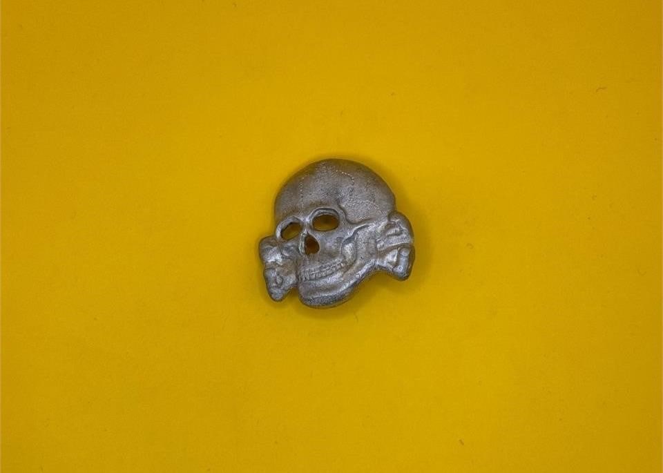 WWII SS Visor Cap Skull - Assmann: Introduced in 1934, the SS visor cap skull replaced the earlier Danziger style skull to distinguish the SS from the SA. Worn throughout WWII by Allgemeine-SS members, it became an iconic symbol of