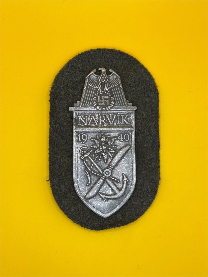 WWII Narvik Campaign Shield - Heer: Awarded to German Heer troops in the 1940 Narvik campaign, this zinc shield features an eagle over "Narvik," with edelweiss, propeller, and anchor symbols. Includes original green cloth backing and